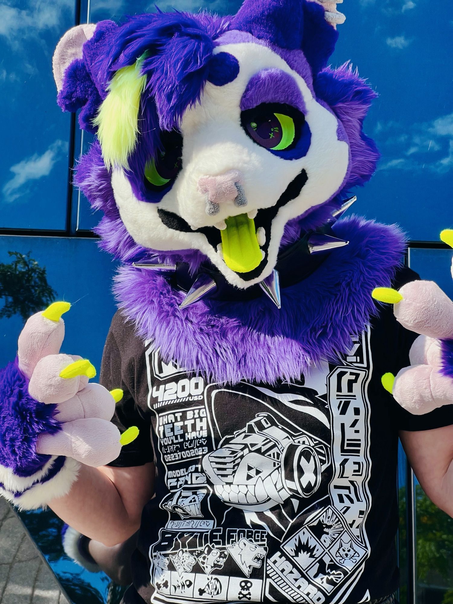 A person in a purple opossum fursuit head and paws poses for the camera