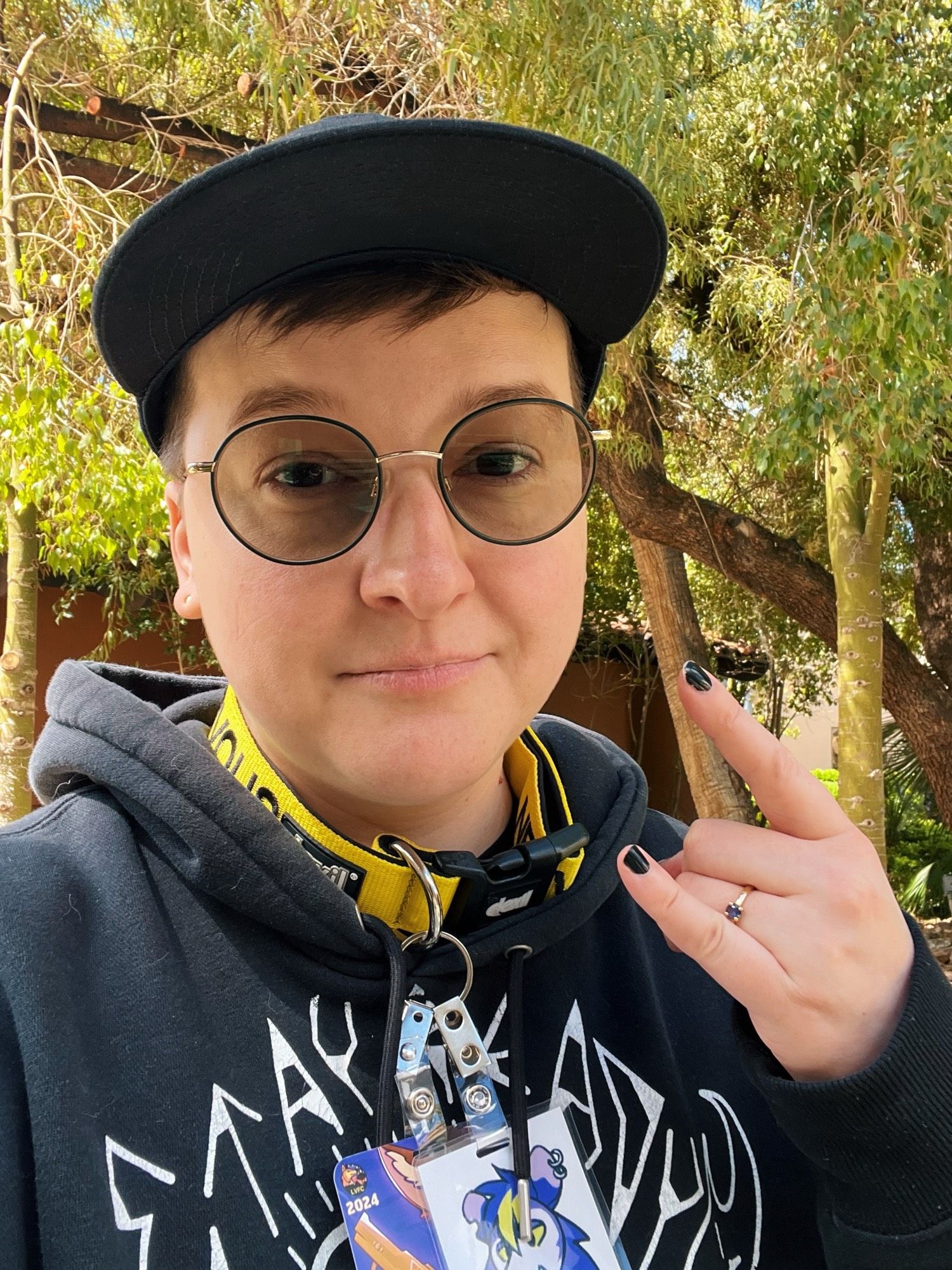 Selfie of a person wearing a black hoodie, baseball cap, and yellow dog collar