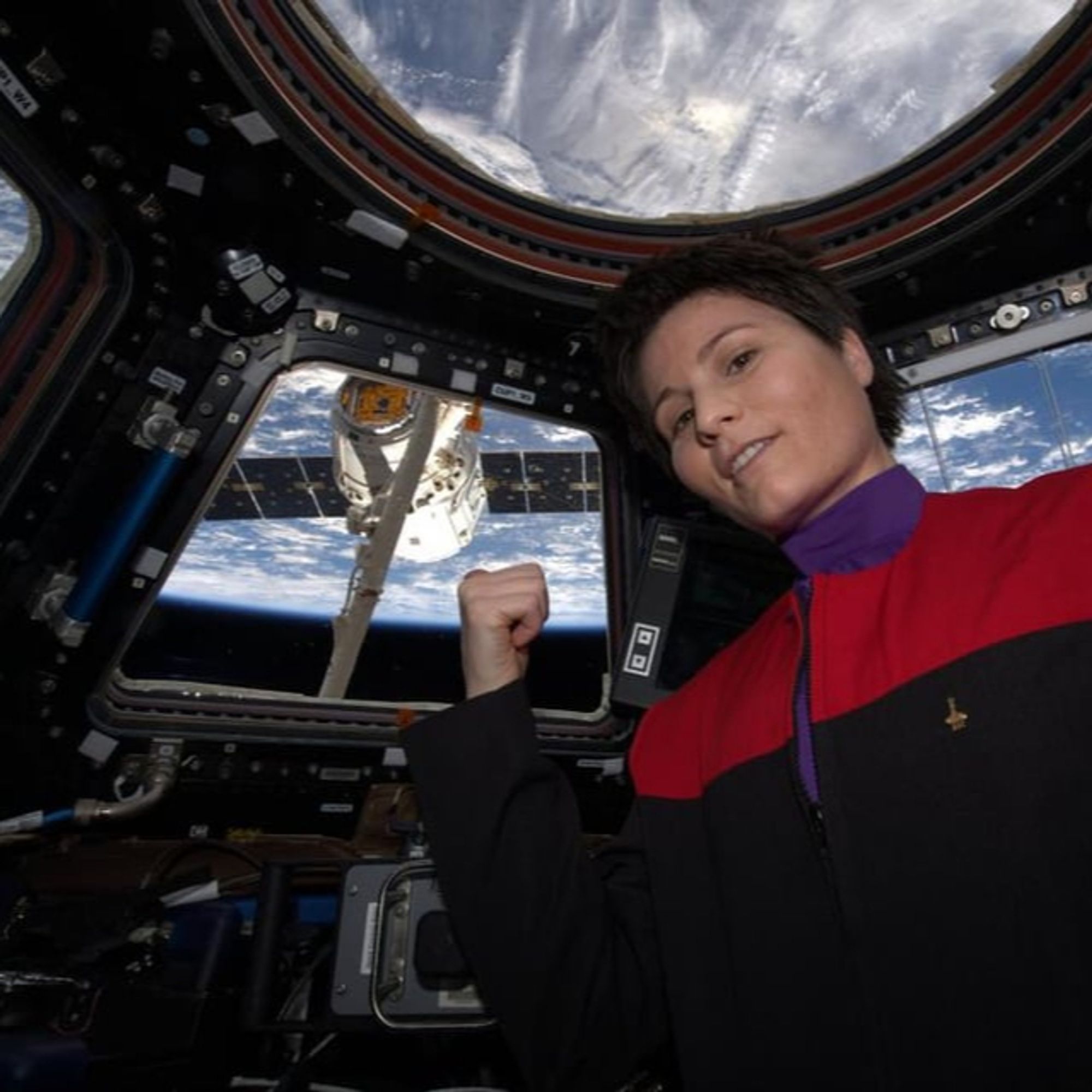 Astronaut Samantha Cristoforetti in a Starfleet uniform poses by the viewport of the International Space Station