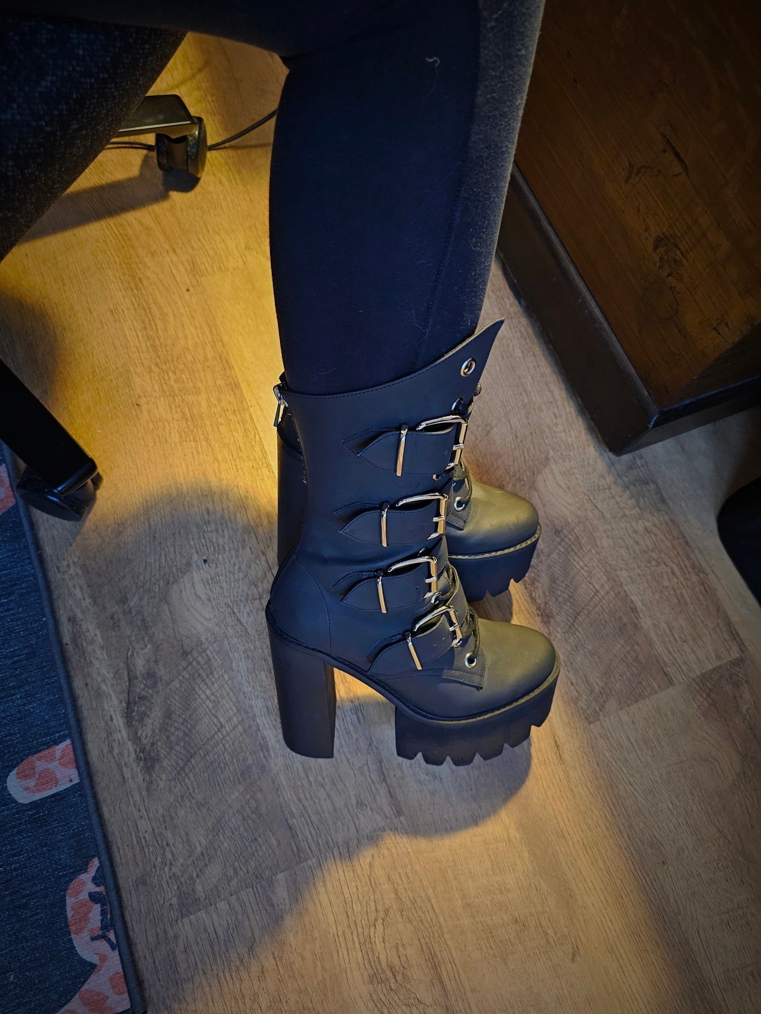 A woman's legs, showing off high-heeled platform calf boots with big buckles