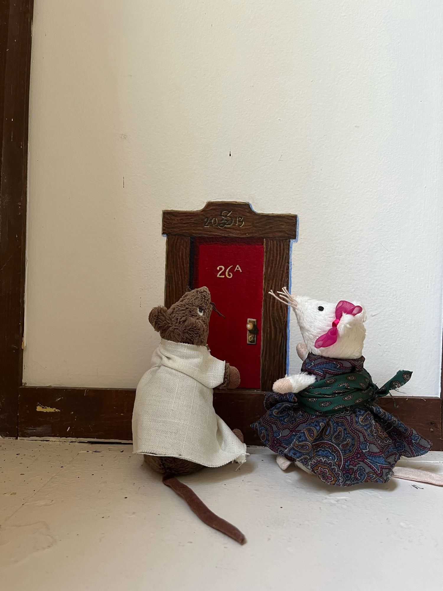 Two toy mice looking at a painted door just their size