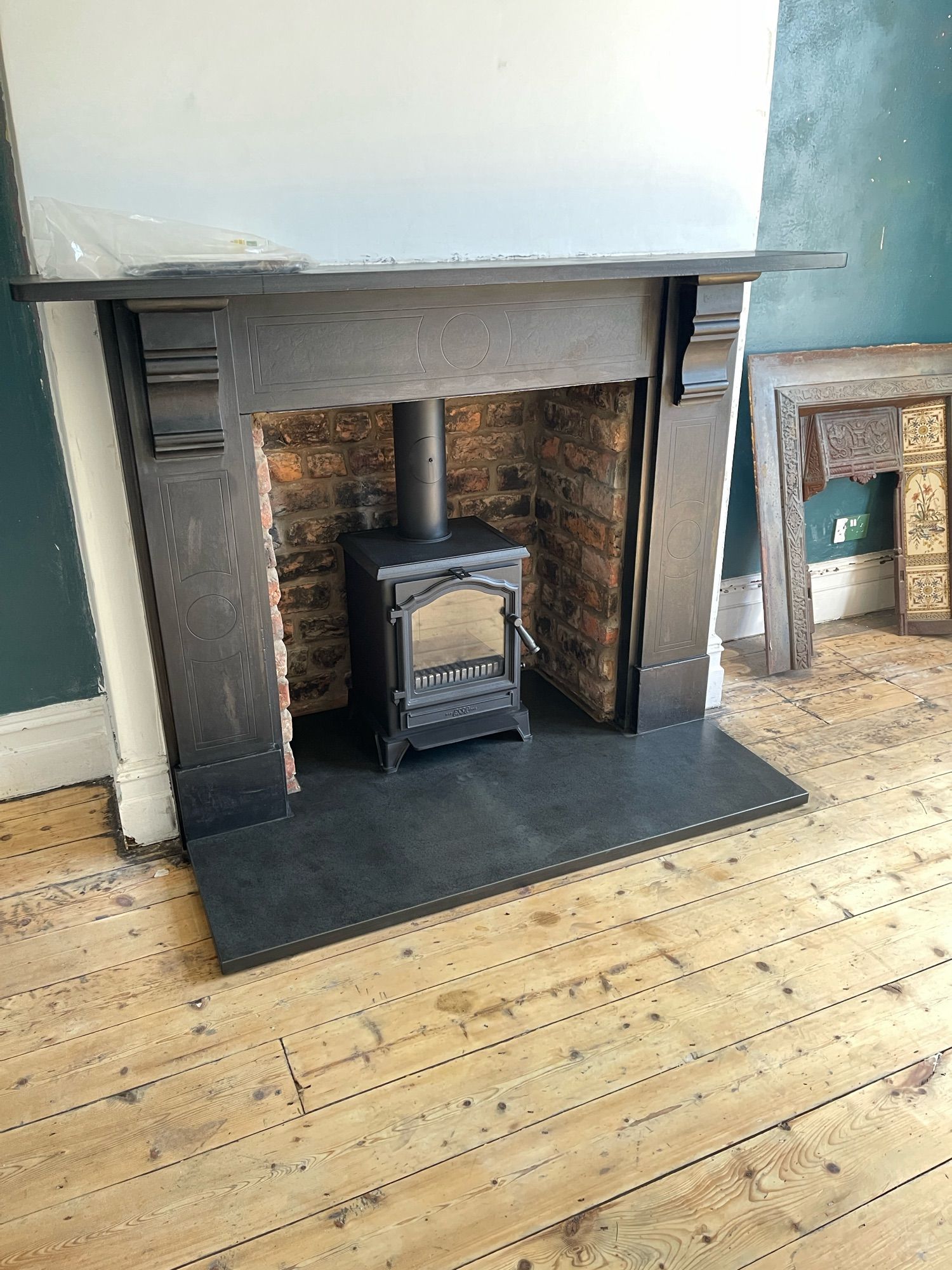 A black log burner in the original Victorian brick fireplace opening, with black slate surround.