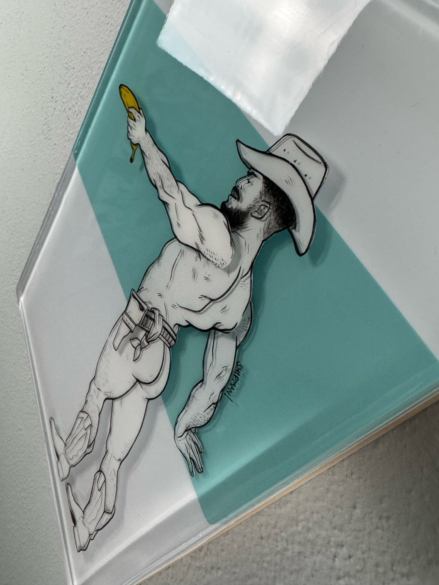 A mixed media resin and acrylic painting. There’s a cowboy facing to the left, left arm outstretched holding a banana like a gun. He’s wearing a cowboy hat, boots and a belt.