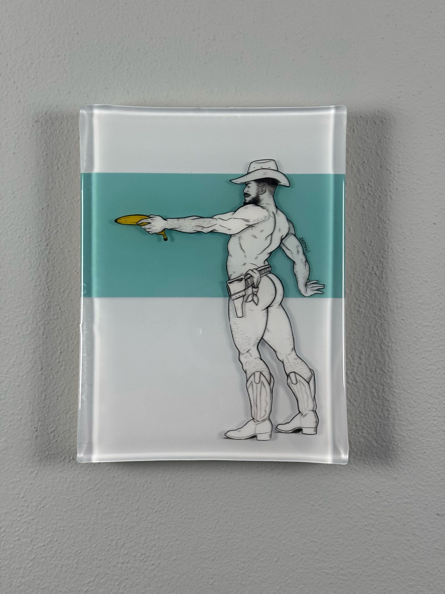 A mixed media resin and acrylic painting. There’s a cowboy facing to the left, left arm outstretched holding a banana like a gun. He’s wearing a cowboy hat, boots and a belt.