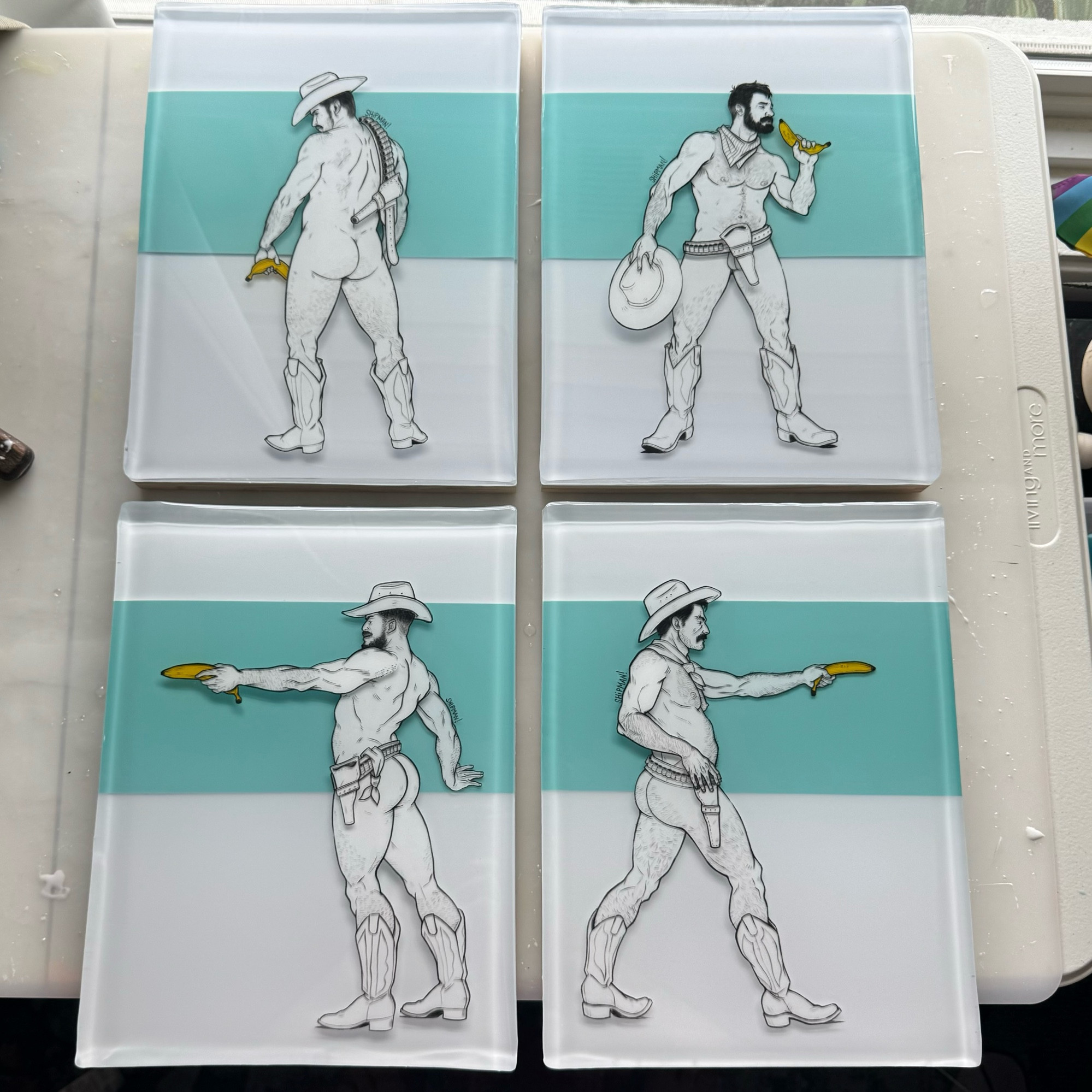 Four mixed media paintings made with epoxy resin and acrylic paint. Each one has a Tiffany blue rectangle across the piece horizontally, on top is a cowboy holding a banana, each is wearing a hat, boots, and a belt.