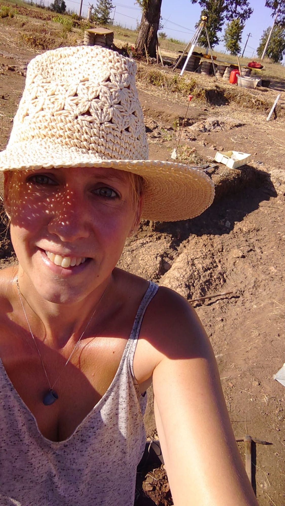 Dr Loes Opgenhaffen smiling, wearing a hat and taking a selfie at an archaeological excavation.