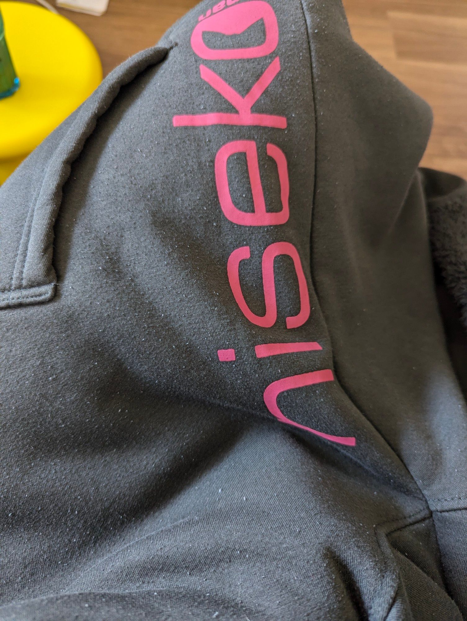 A dark grey jumper covered with white nubbly bits. The word NISEKO is in hot pink letters