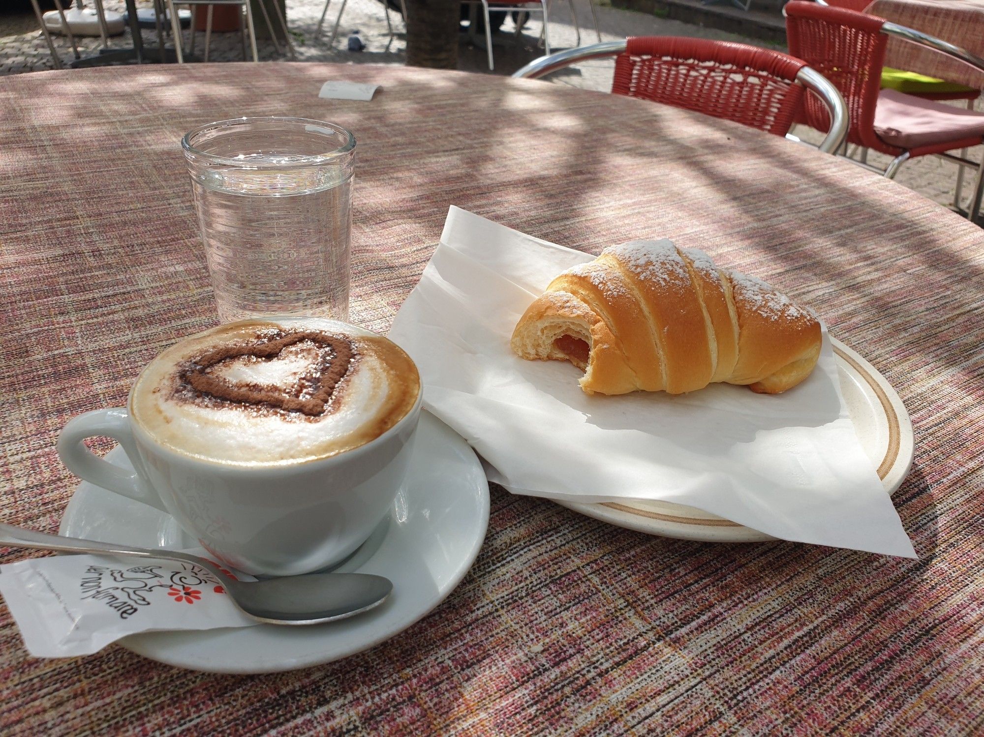 Cappuccino mit Herzdecor aus Schokopulver mit süßem corneto.