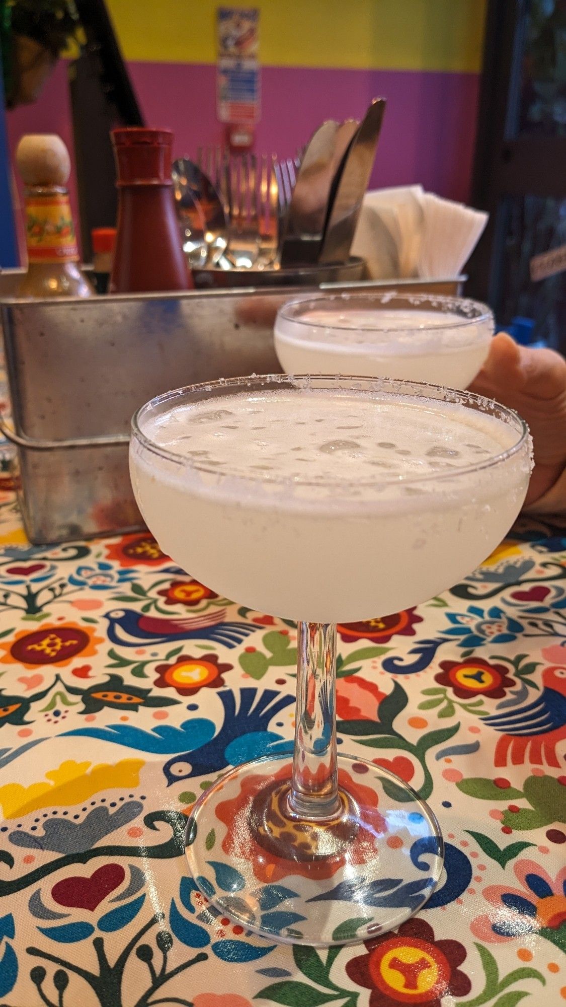 Two margaritas on a bright multicoloured restaurant table cloth