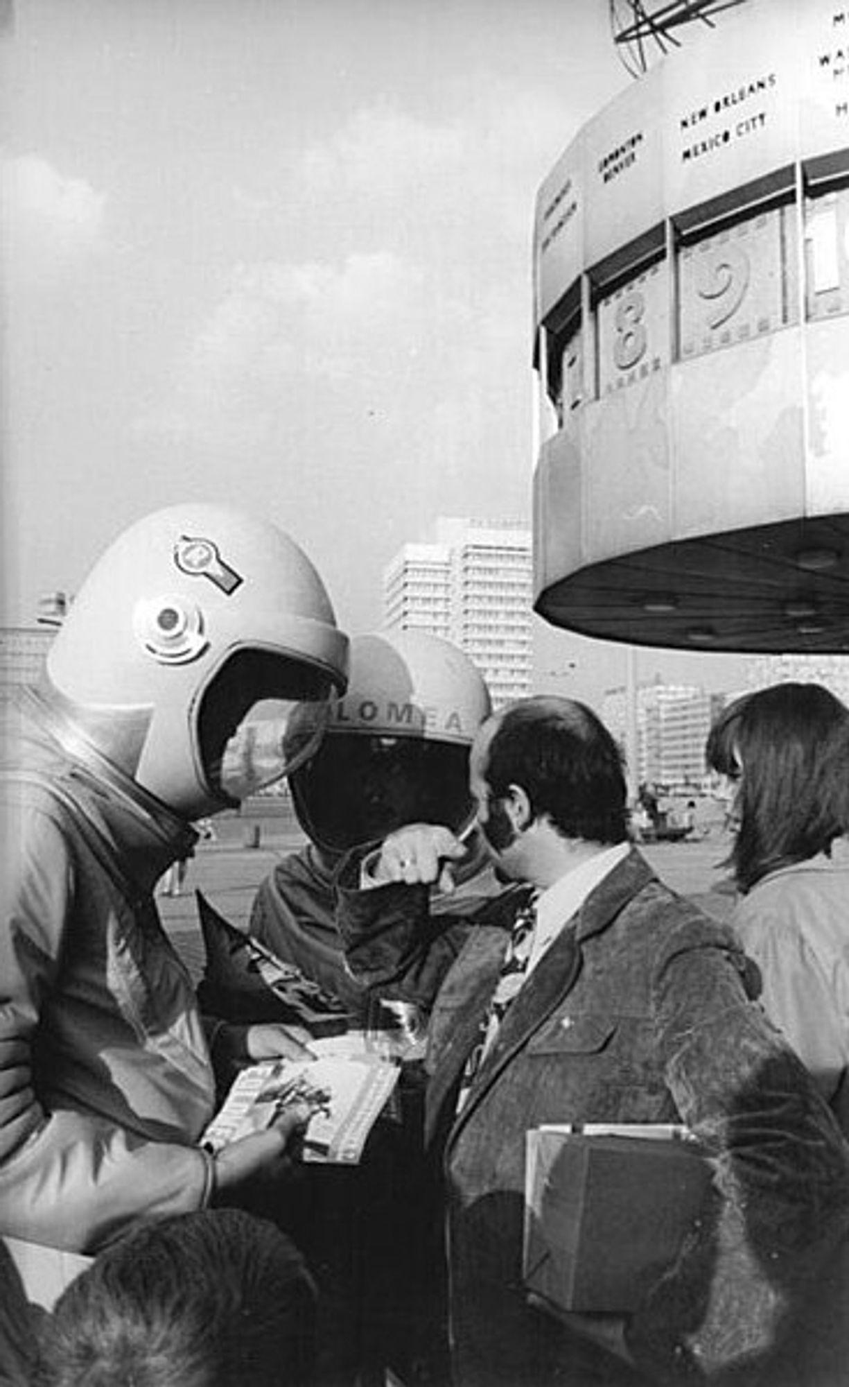 berlin, Alexanderplatz, weltuhr, im vordergrund personen in raumanzügen im filmdesign
Bild: Bundesarchiv via Wikipedia, Kooperation zwischen BArch und WikiCommons, Nutzung gemäß free use agreement
Link: https://commons.wikimedia.org/wiki/File:Bundesarchiv_Bild_183-L0920-0032,_Berlin,_Alexanderplatz,_Filmwerbung.jpg