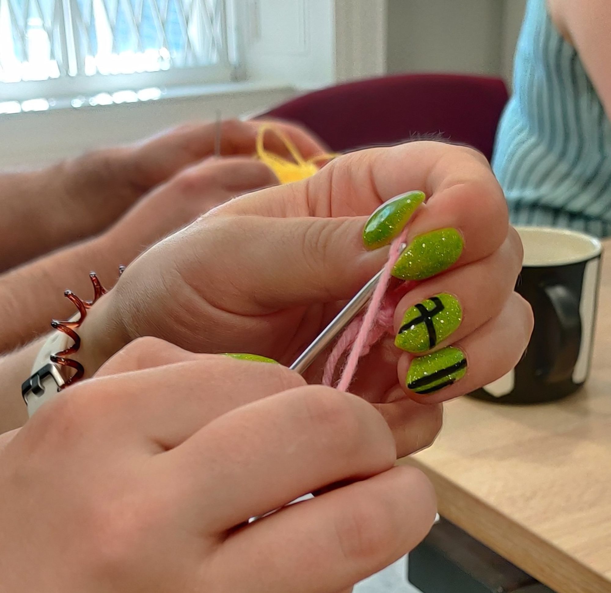 An attendee's hands in close up as she crochets with pink wool.