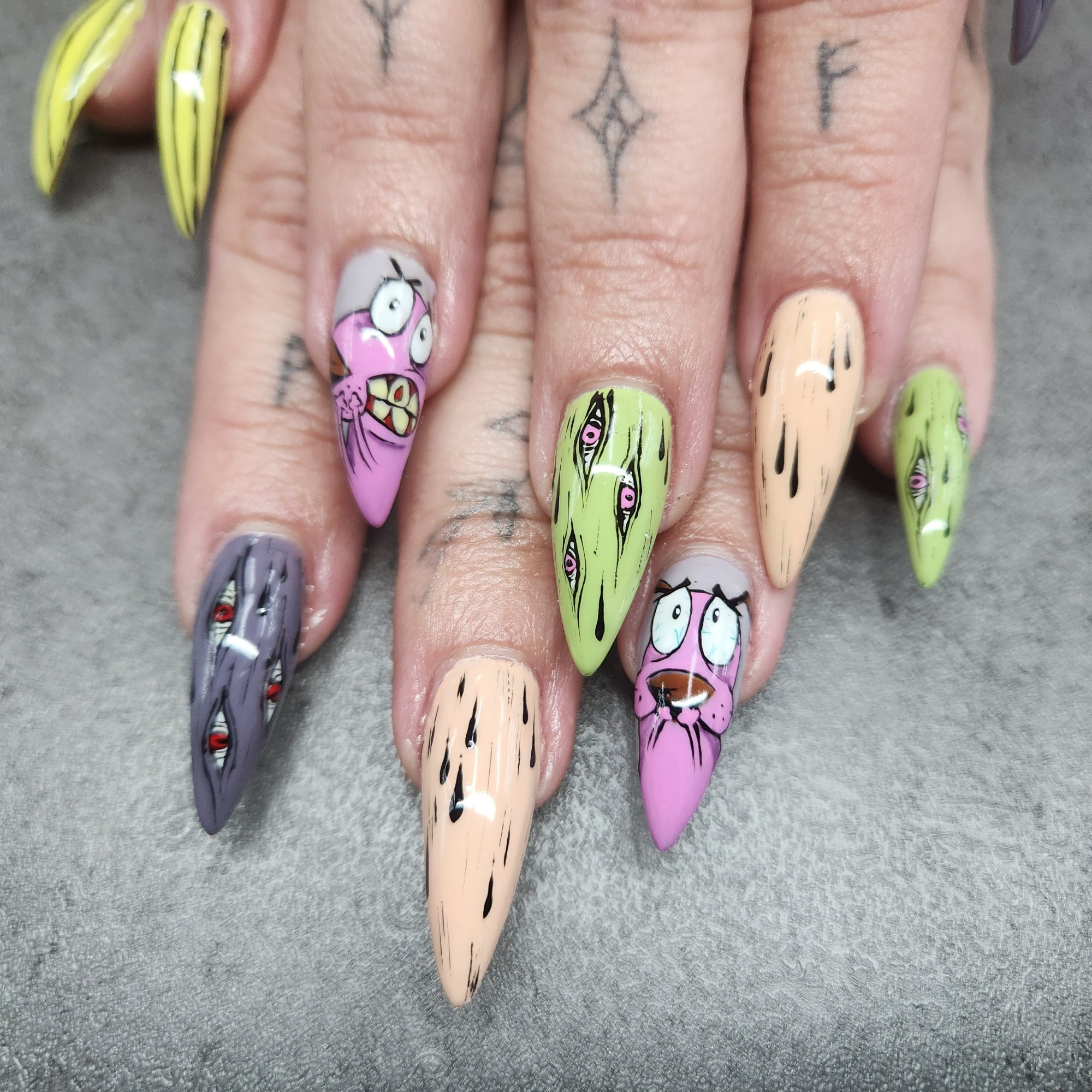 Picture of hands with long pointed nails, with Courage the Cowardly Dog nail art.