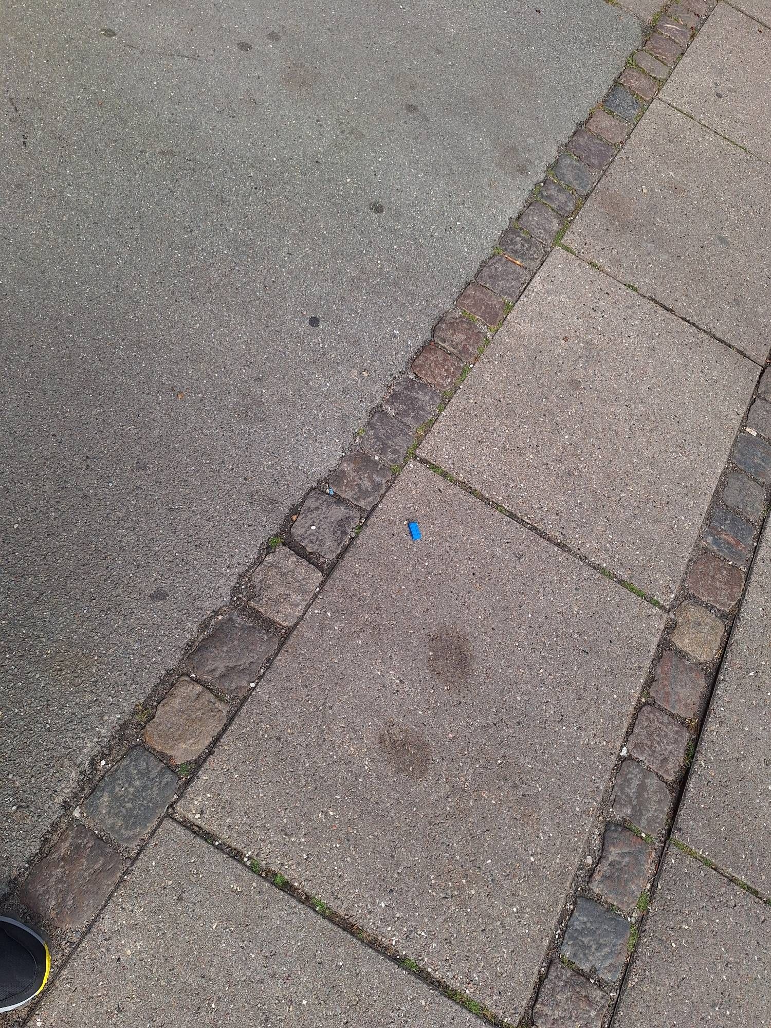 A blue Lego block sitting in the middle of a sidewalk in Copenhagen.