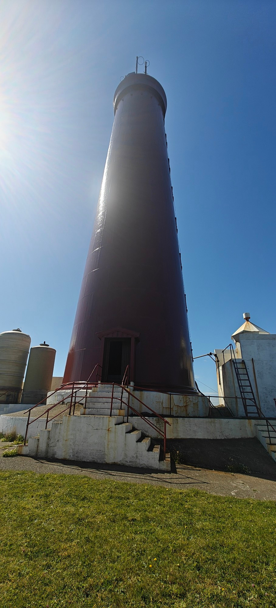 Photo of a Lighthouse, taken from the base. It's tall and dark red