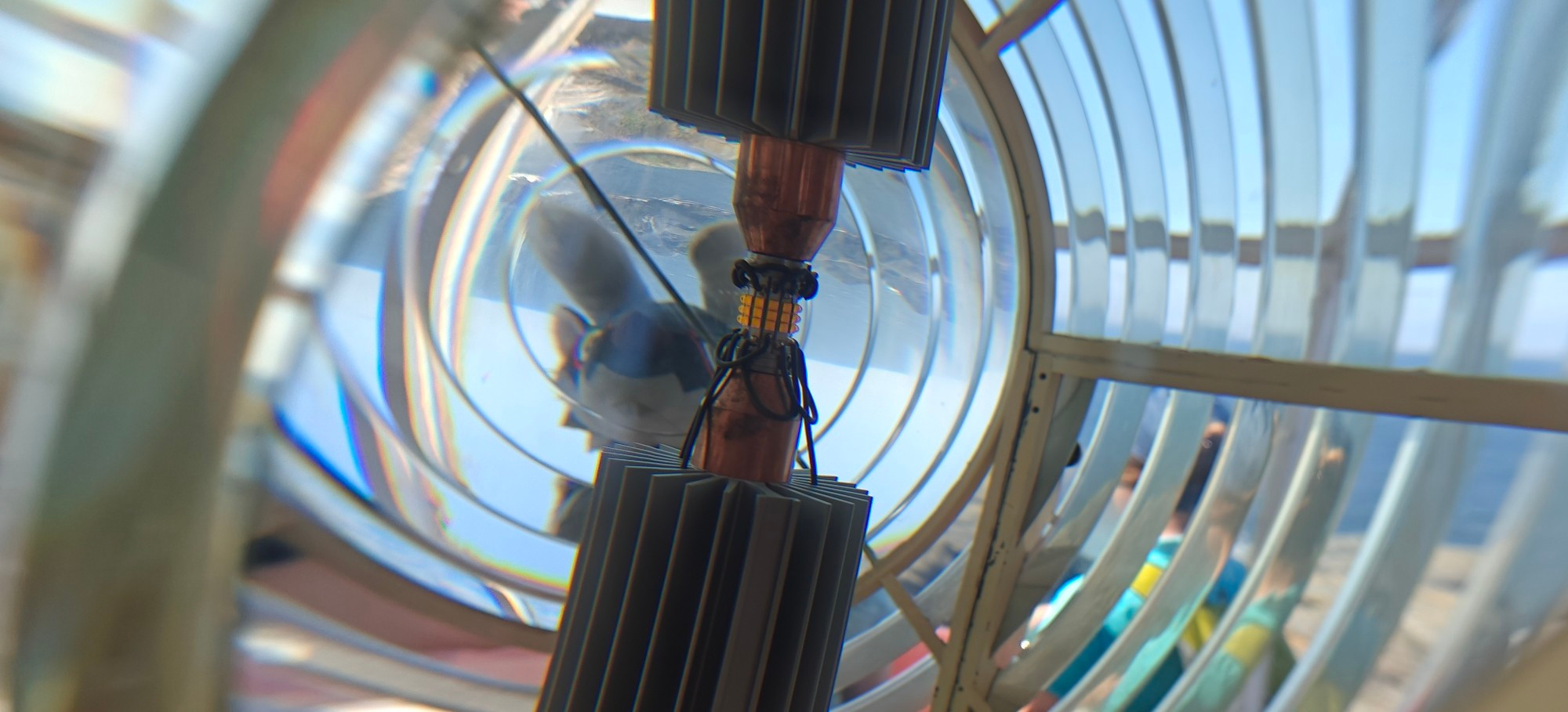 Photo of Deformed Stygian Zinogre plushie taken through the Fresnel Lenses of a Lighthouse. You can see the plushie behind the LED Light Source