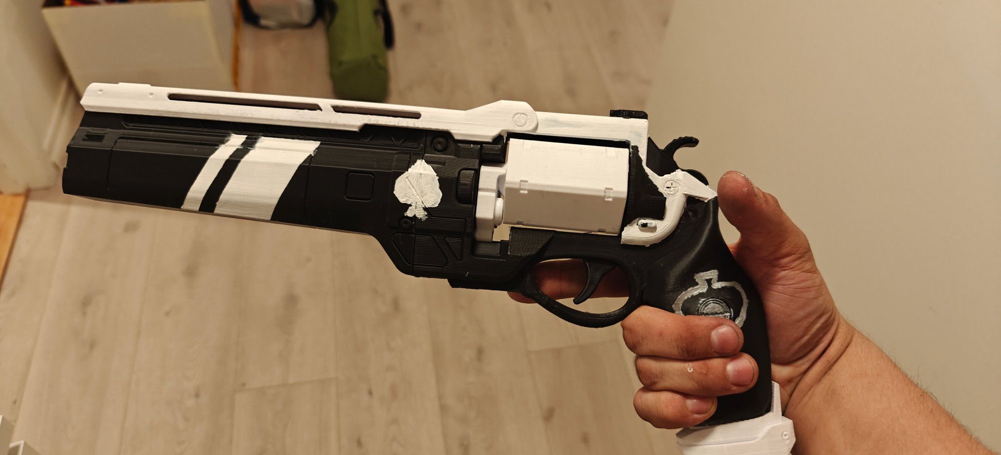 Side view of a 3D Printed black and white hand cannon from Destiny. It has two spades painted on the side, one on the barrel and the other on the grip