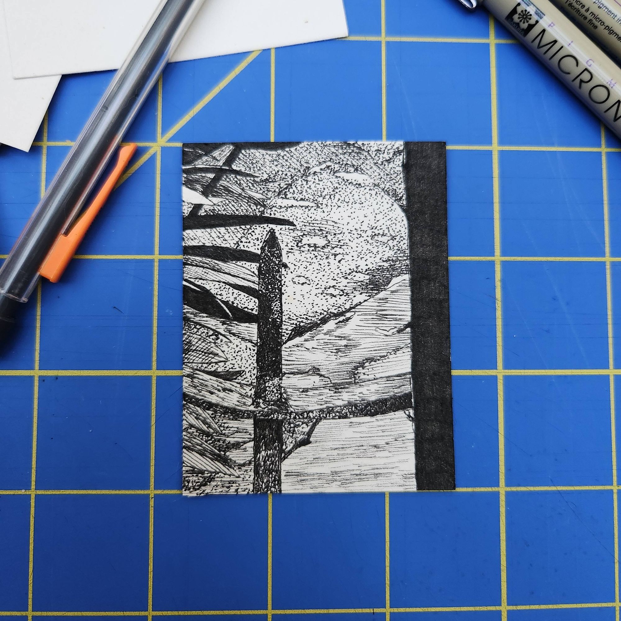 a 2.5" by 3" pen drawing of a close up bit of fencing in front of pavement with some leaves on the left side of the drawing.
#ioanainktobermystery