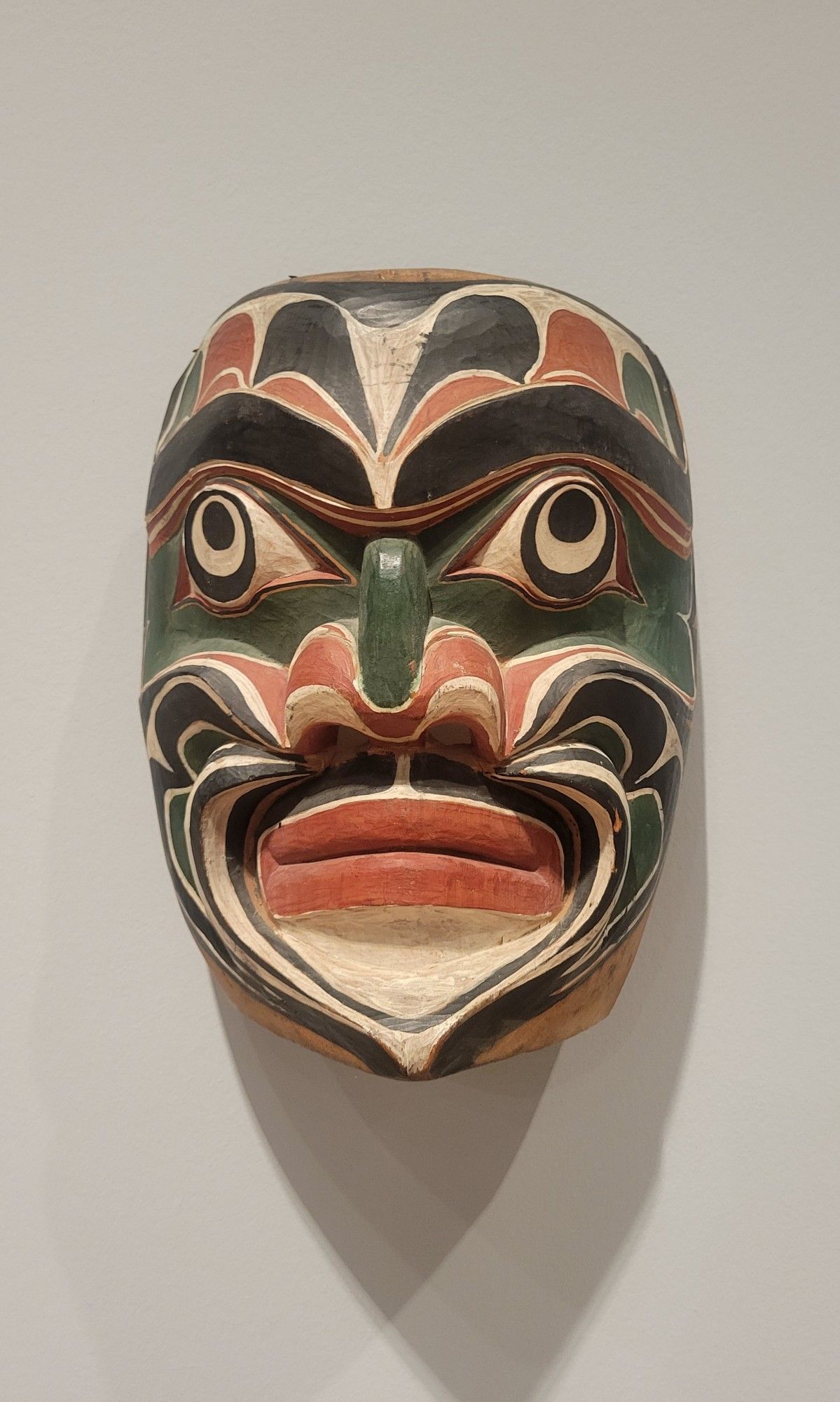 Chief George is respected as one of the artists who persevered through the potlatch prohibition year (1885-1951), diligently creating work for ceremonial use. He often carved his figures with upward-looking eyes, which became his trademark. Such eyes can represent either spiritual possession or looking upward from the depths of the ocean. The deep hollows in the cheeks are painted with lines representing gills. Flowing upward from the cheeks and above the eyebrows are U-shaped designs that suggest fish scales or rolling waves.

western red cedar with natural pigment paints 