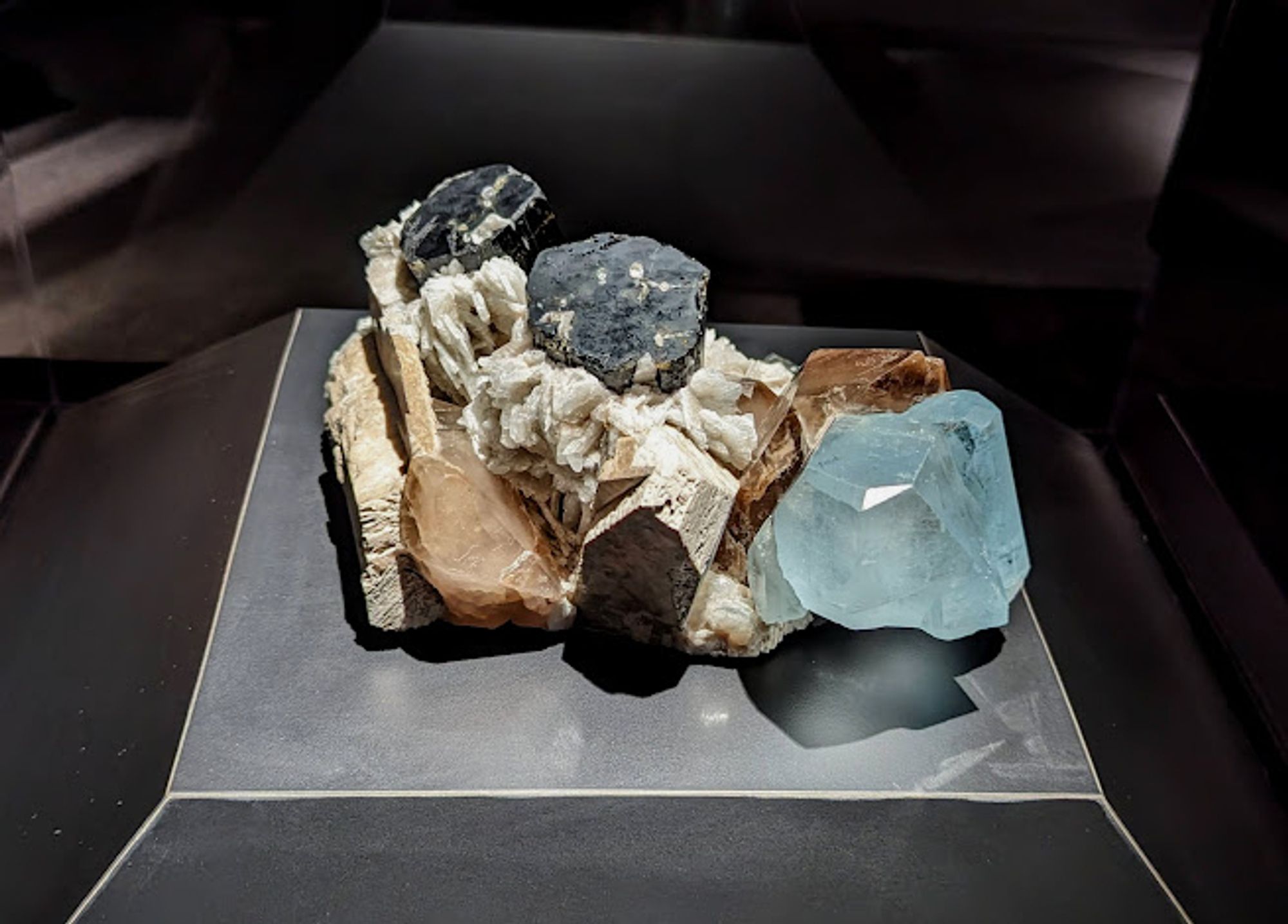 Cluster of minerals including striated elbaite tourmaline, translucent smoky quartz, white albite feldspar, and blue tourmaline.