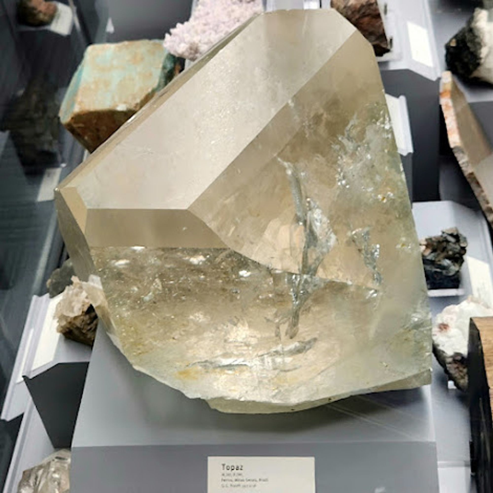 Large topaz crystal with a nice crystal form. The top of the topaz is frosted and the rest of the body of the crystal is transparent to translucent, and shows a lot of internal bubbles. It is champaign-colored, though the coloration isn't consistent throughout.