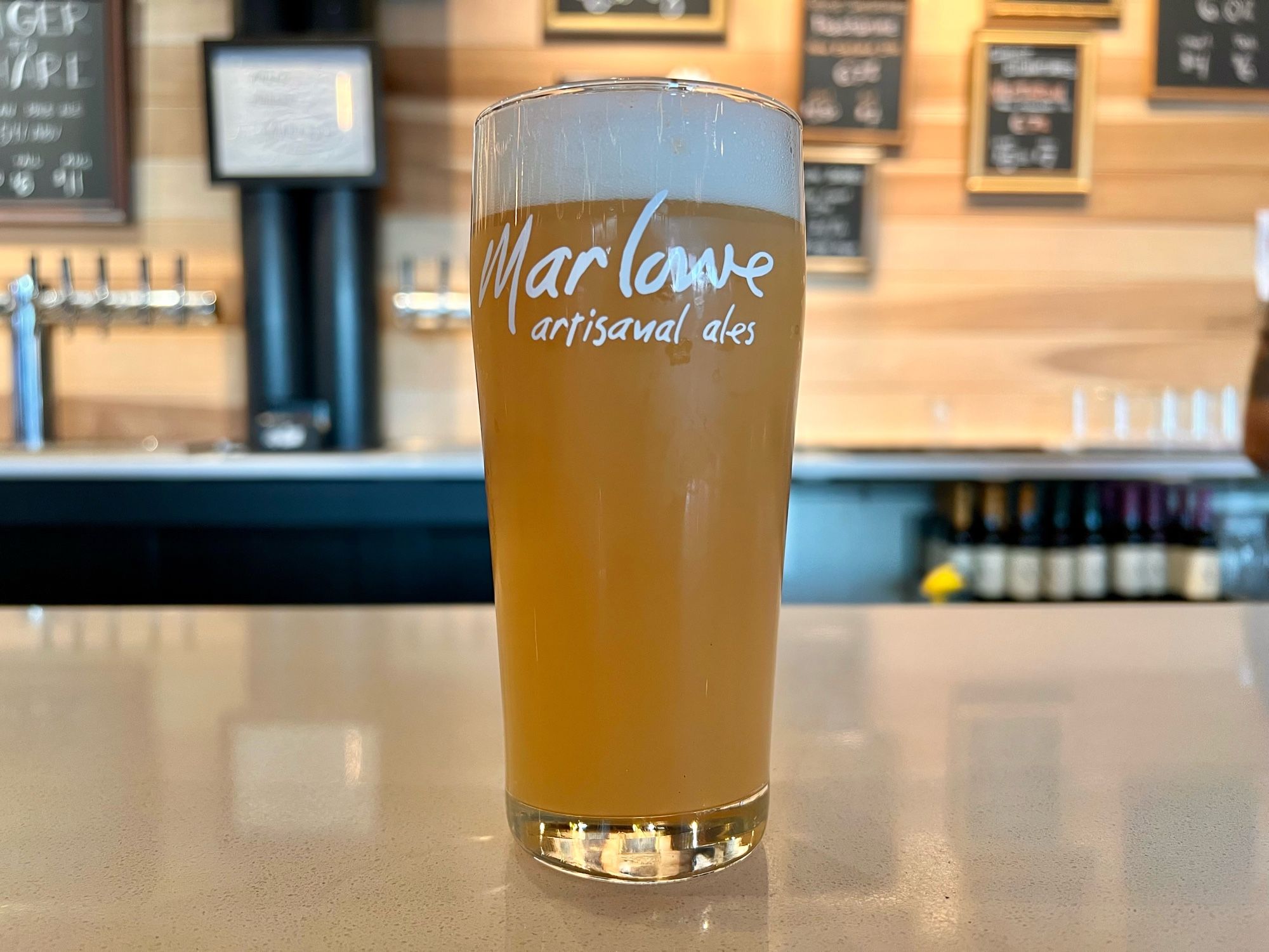 A tall glass of a hazy pale ale with the logo of Marlowe Artisanal Ales on it