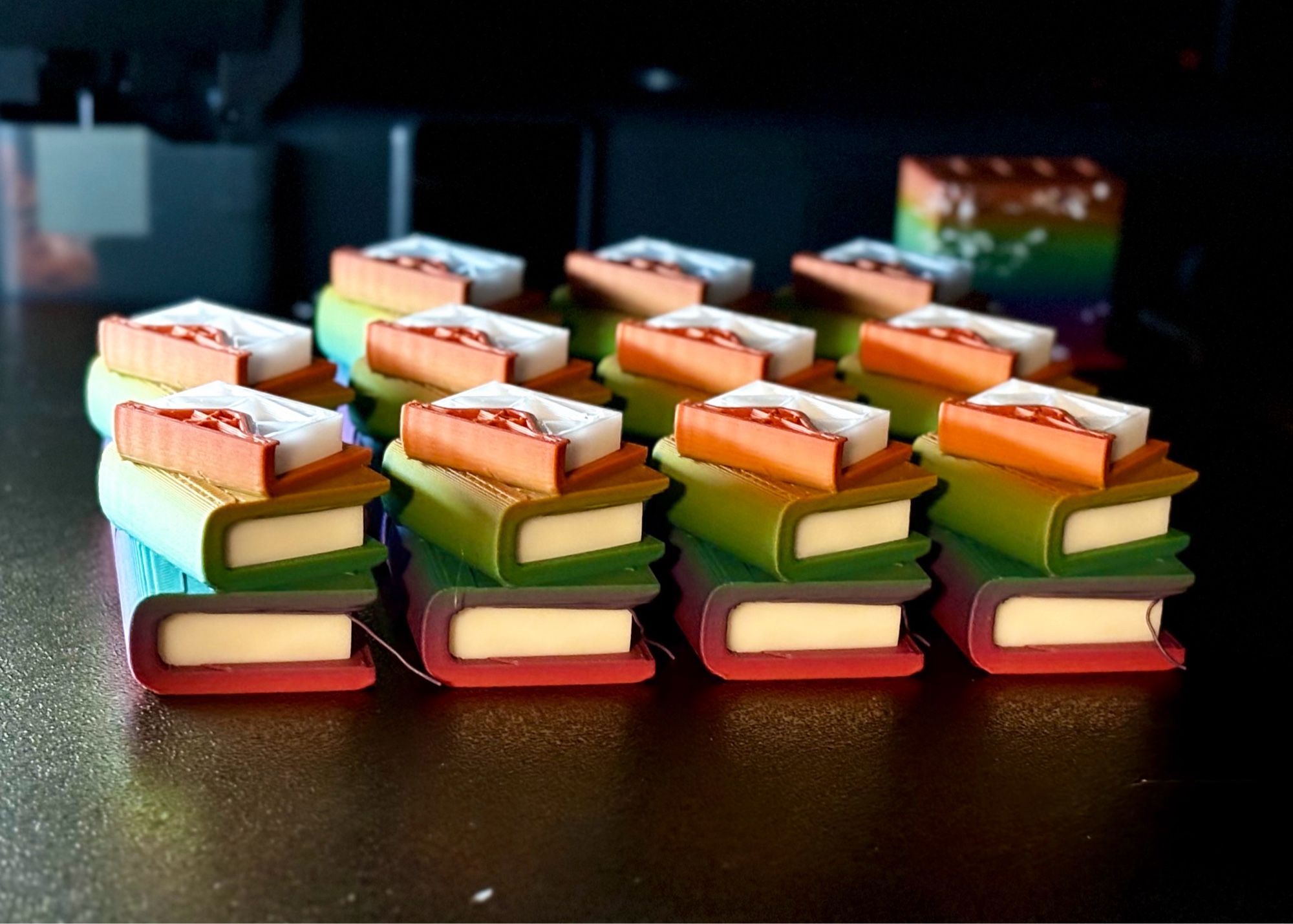 An in-progress 3D print of a rainbow stack of books