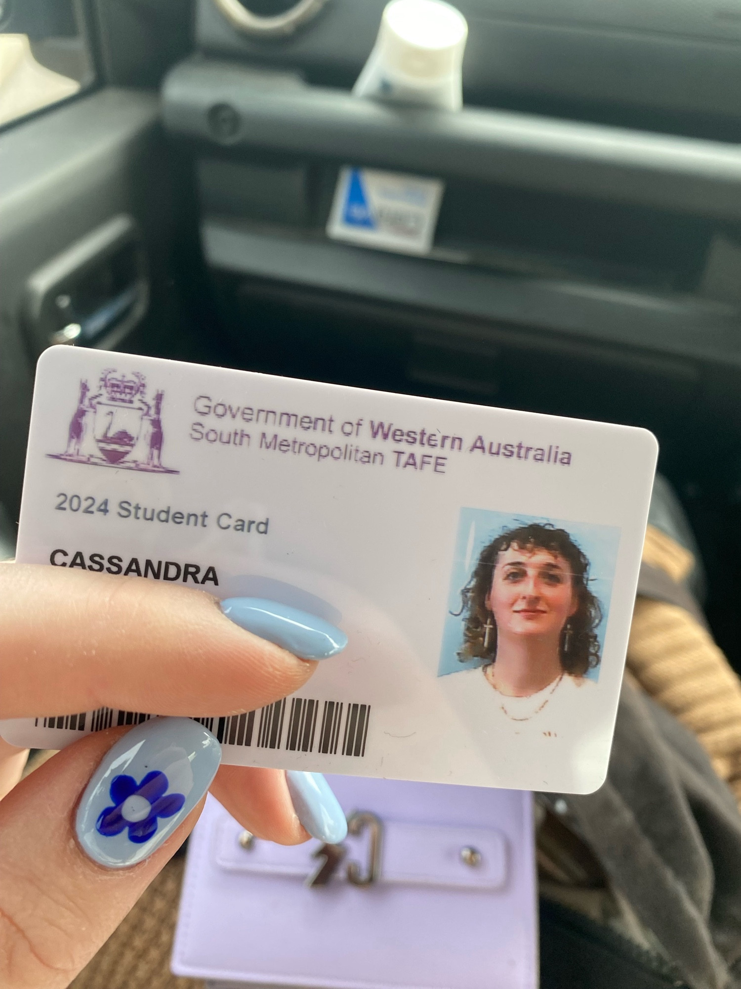 image of cassie holding her student id with a finger covering some information