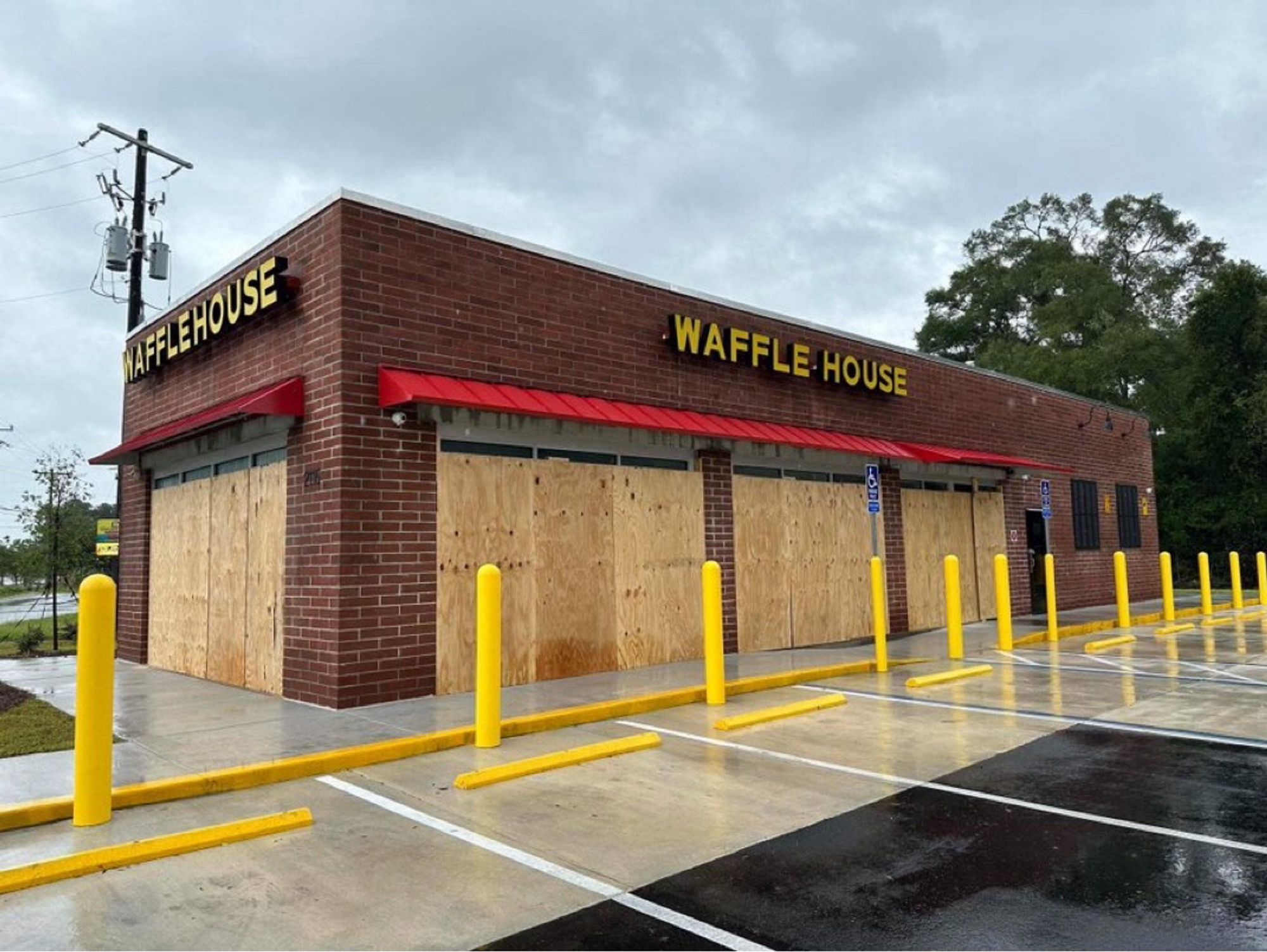 Photo of a closed Waffle House with its windows boarded up and an empty parking lot.