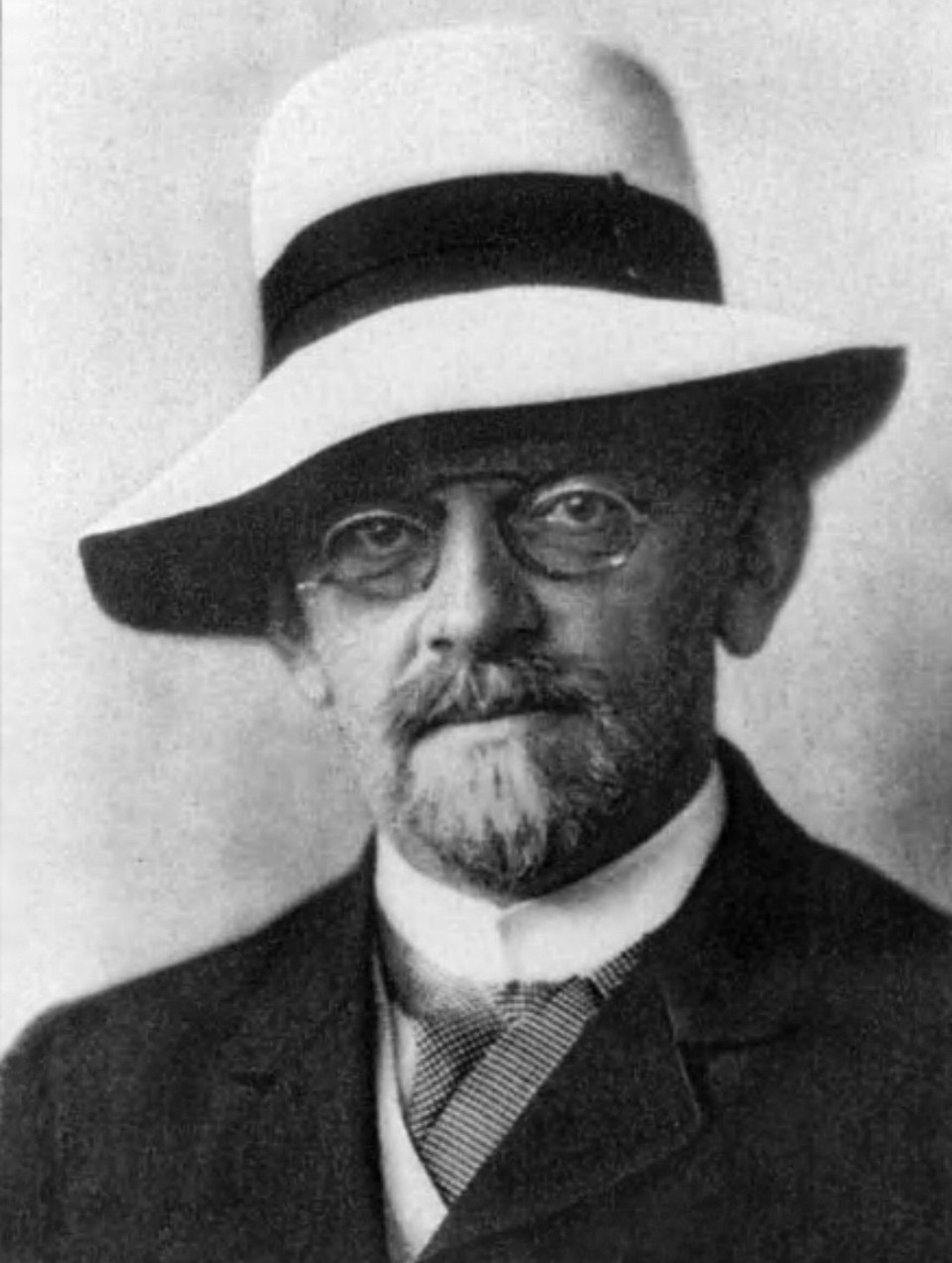 A bearded German mathematician and philosopher of mathematics David Hilbert wearing a large brimmed hat and wearing spectacles. Hilbert was one of the most influential mathematicians of his time in his own right and was the doctoral advisor and colleague at Göttingen of some of the most notable mathematicians of the 20th century.