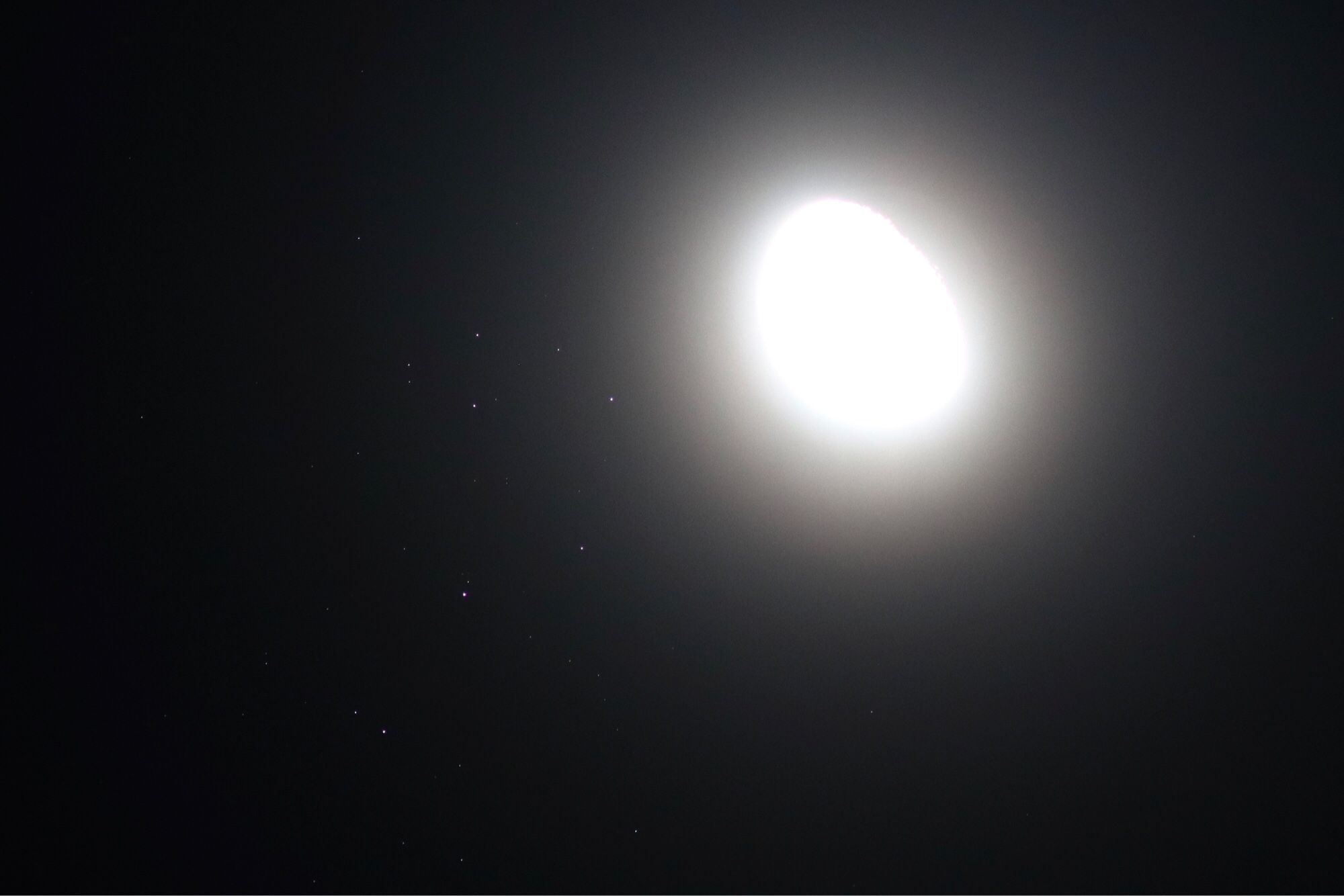 A very overexposed waning gibbous moon, just to the right of the Pleiades star cluster