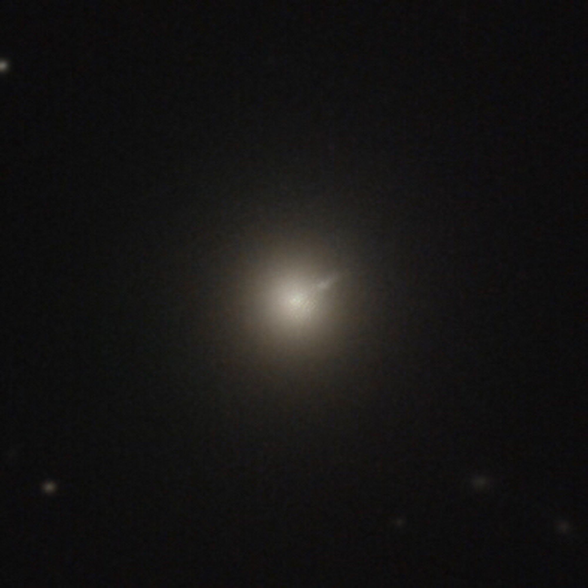 Elliptical galaxy M87 and its plasma jet, seen here as a fuzzy round blob of light, bright in the center, with a thin, diffuse ray extending from the center to the upper right, ending where the rest of the galaxy fades into the black background