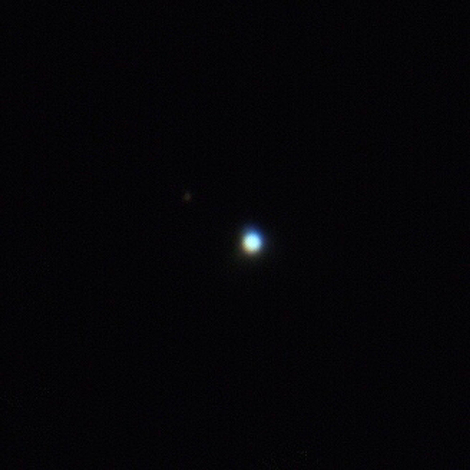 Neptune and its largest moon, Triton, seen as a small bright, mostly white dot, with a smaller, faint dot to its upper left, against a black background