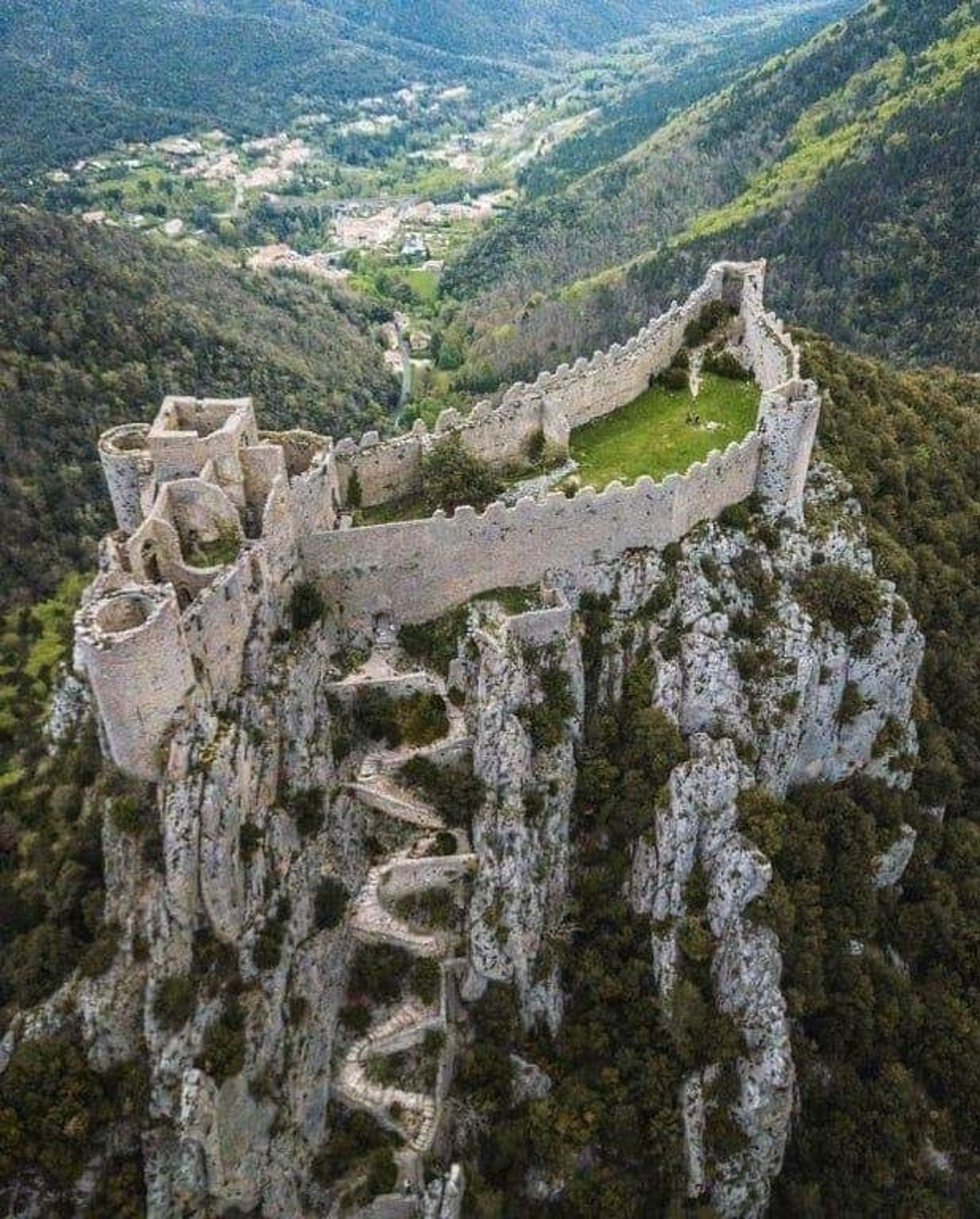 Overhead view of the 12th century castle perched on an inaccessible rocky promontory with a tiny widi g staircase leading up to it