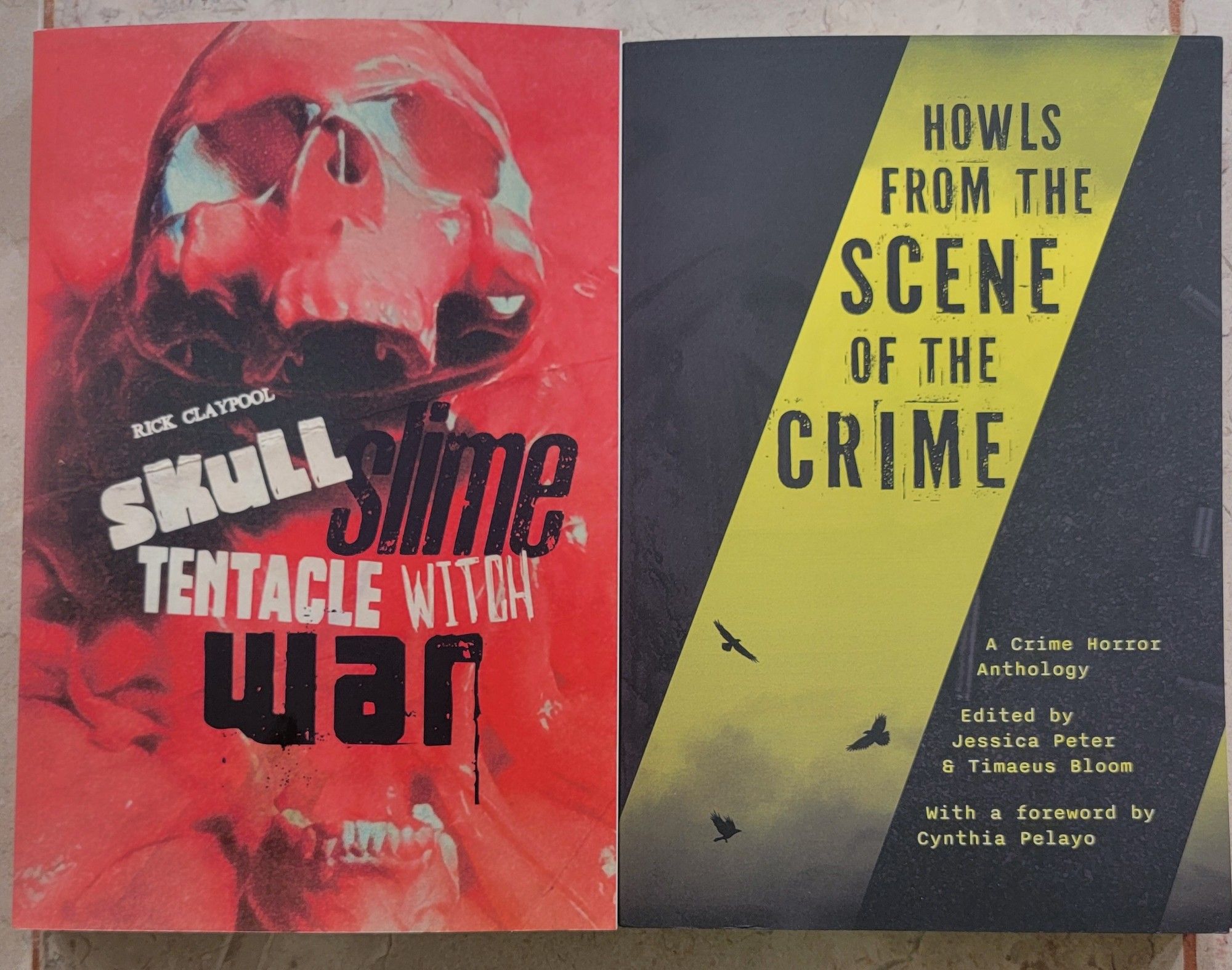 Picture of 2 books. Left book is Skull Slime Tentacle Witch War by Rick Clay pool, red cover with a Skull on it. Right book is Howls from the scene of the Crime edited by Jessica Peter and Timaeus Bloom, black cover with yellow diagonal stripes, like Crime scene tape, with birds flying.