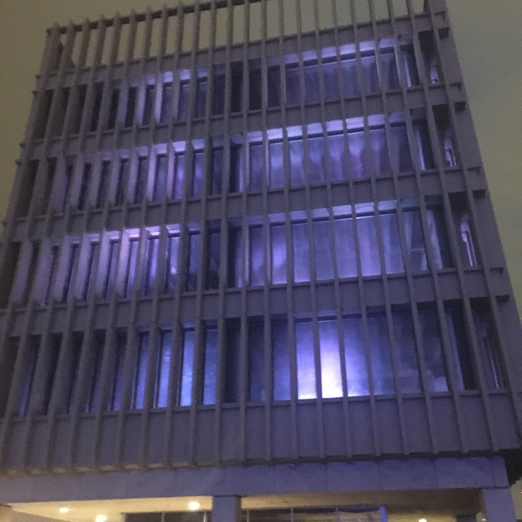 Old USPS distribution building lit with purple lights on a dark & rainy night