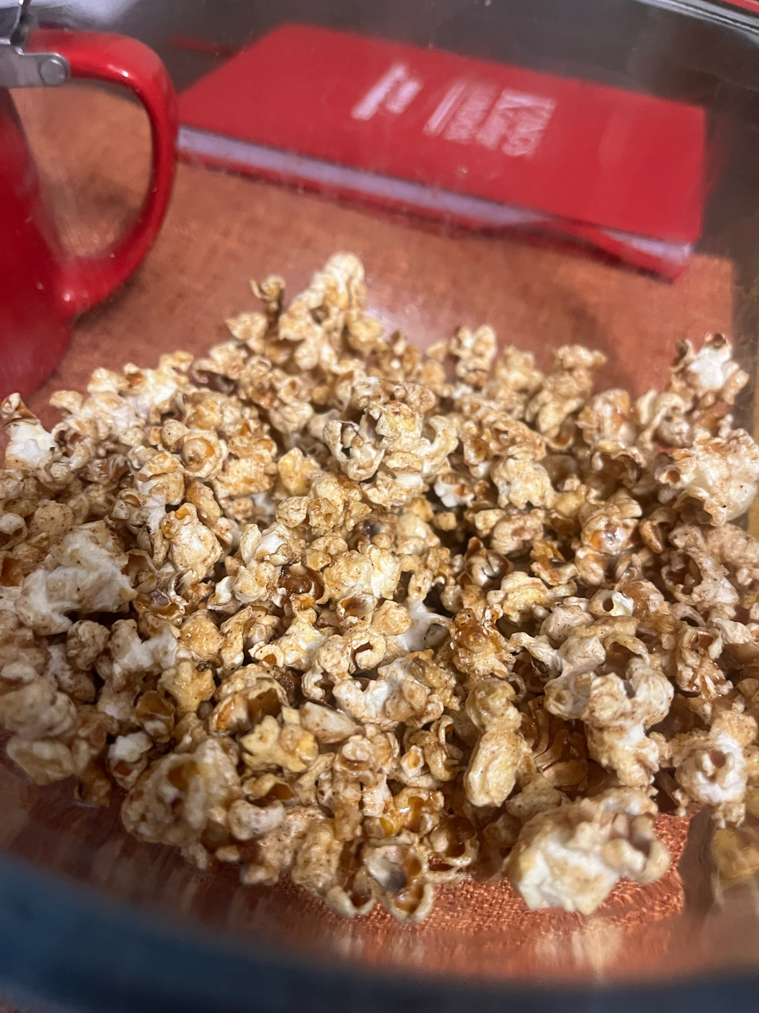 Golden popcorn in a glass bowl, tea pot and notebook visible in the background 