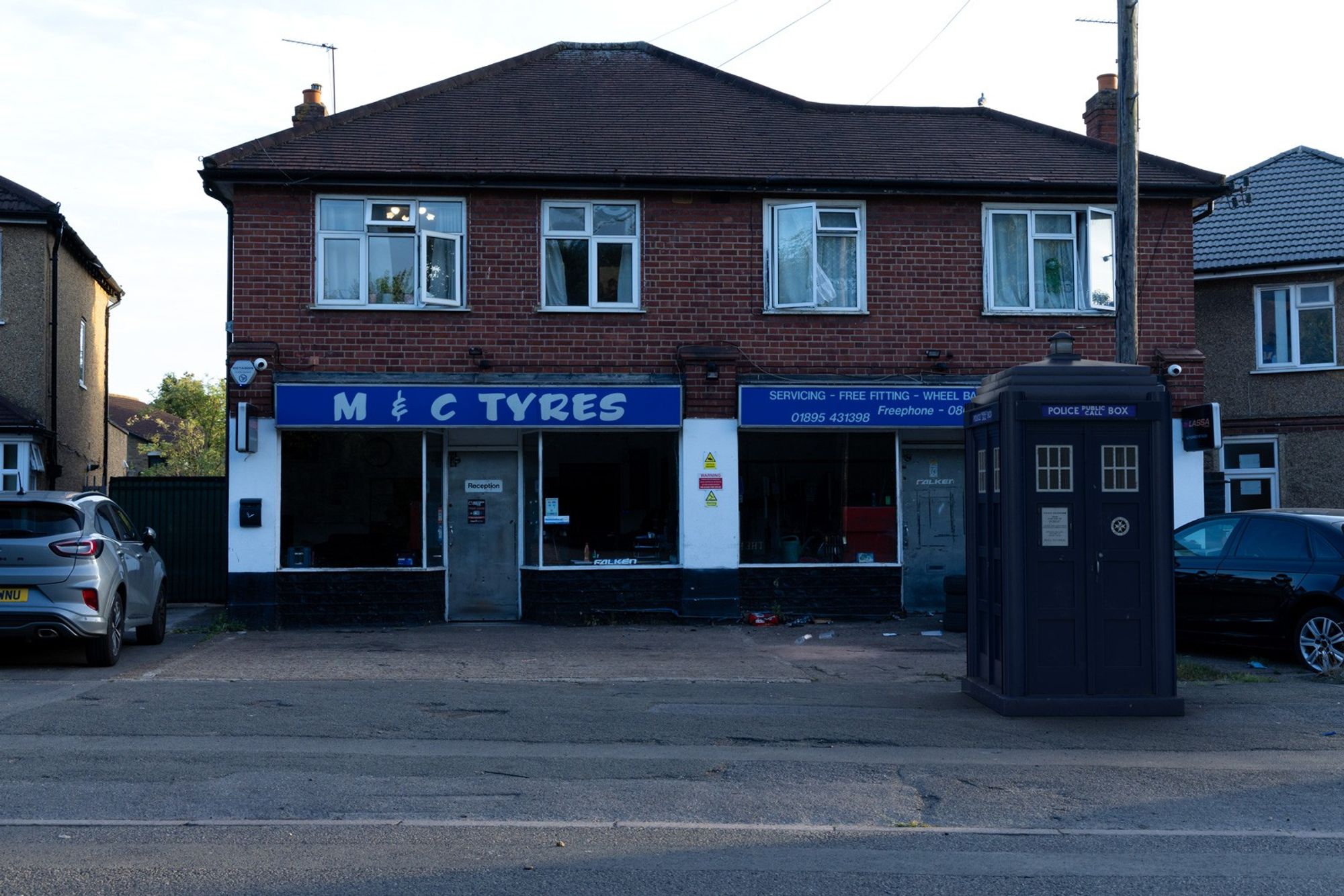 A 3D composite of a police box in front of a house with accommodation on the first floor and a tyre business on the ground floor.