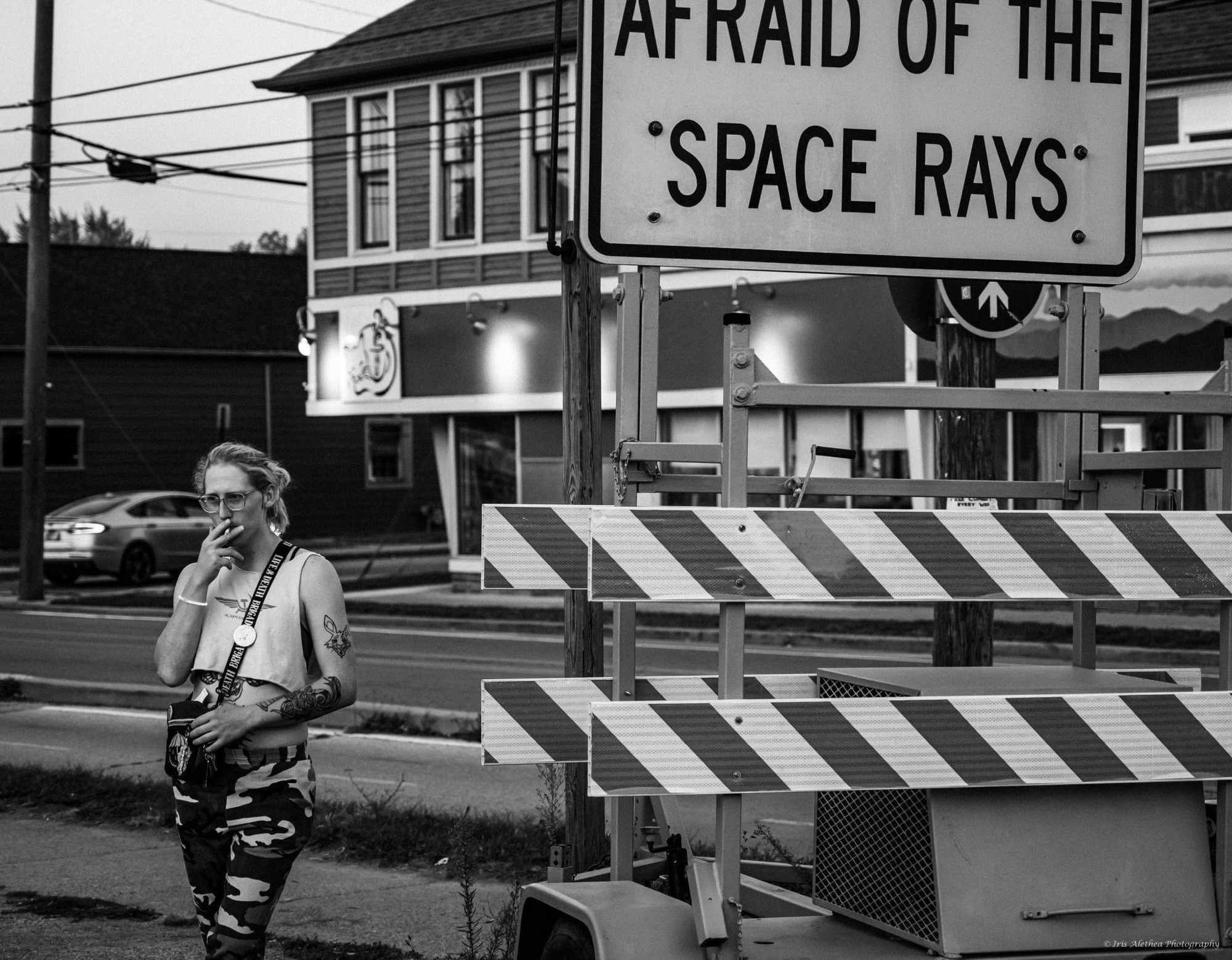 Photo of me smoking next to a sign that says “don’t be afraid of the space rays” it’s Greyscale 