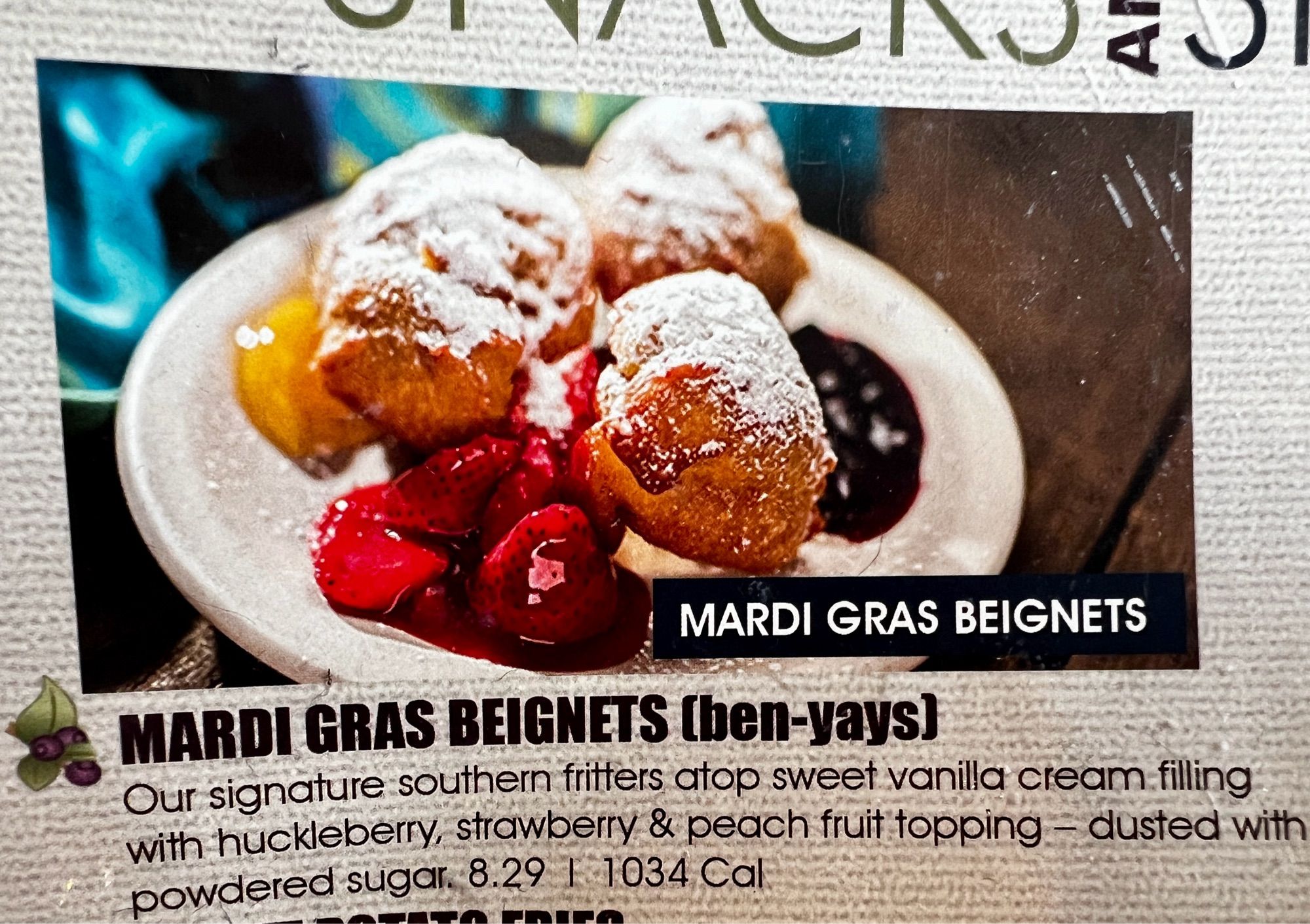 MARDI GRAS BEIGNETS*
MARDI GRAS BEIGNETS (ben yays)
Our signature southern fritters atop sweet vanilla cream filing with huckleberry, strawberry & peach fruit topping - dusted with powdered sugar. 8.29 | 1034 Cal

It’s actually on there twice.