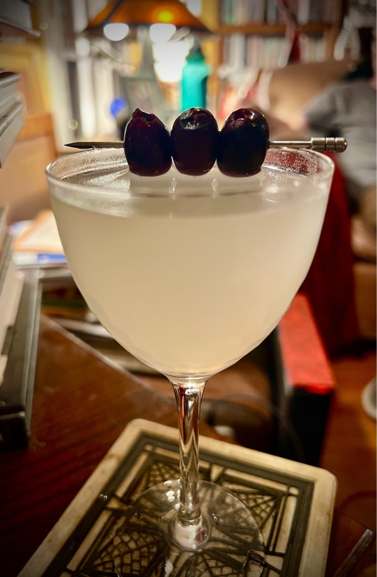 A closeup of one of our Icelandic Martinis, the three Kalamata olives on a cocktail pick balanced on the rim of the glass.