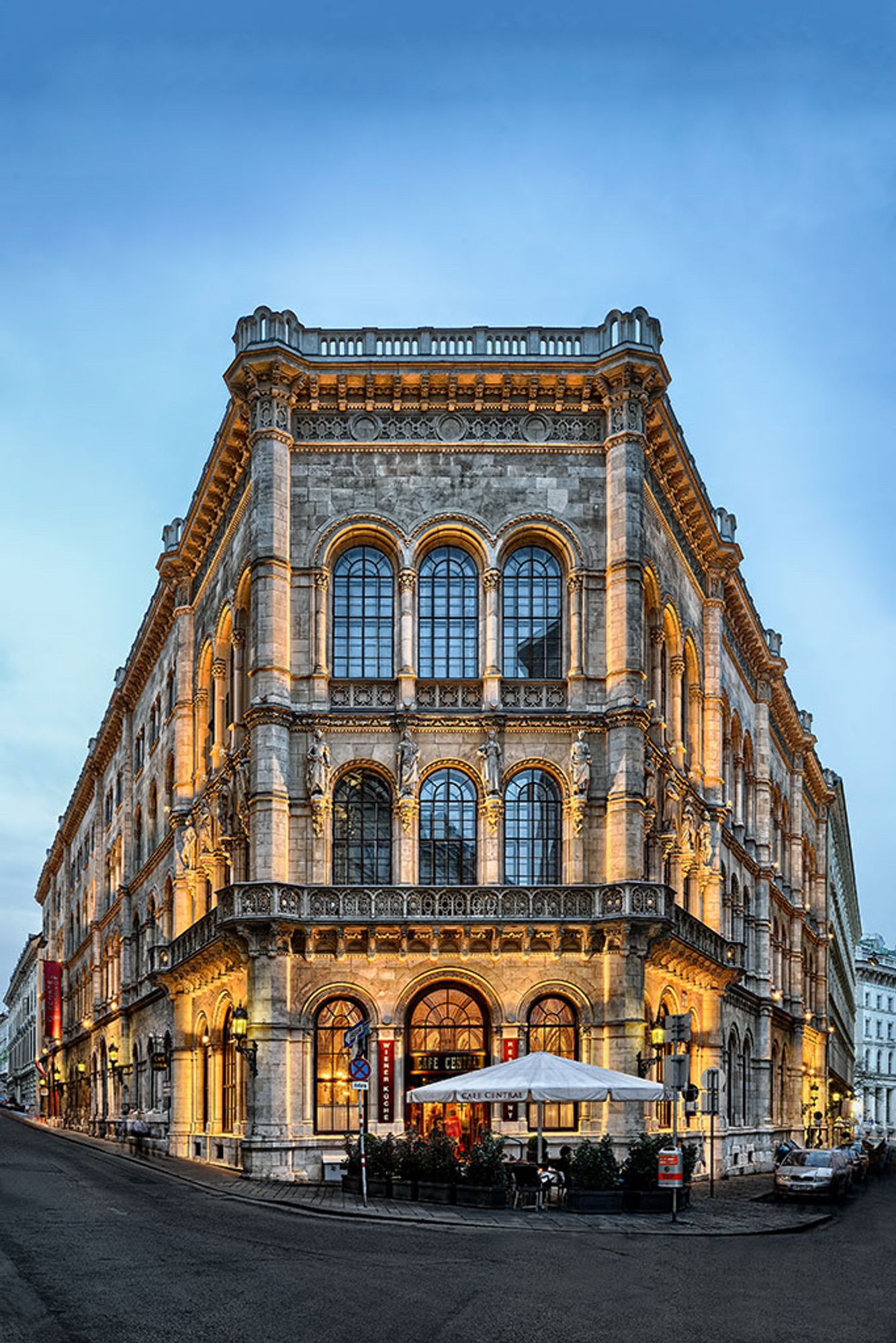 Ein altes Gebäude mit einer wunderschönen verzierten Fassade und großen Rundfenstern. Es hat Säulen an der Front. Und kleine balkonartige Vorsprünge. 