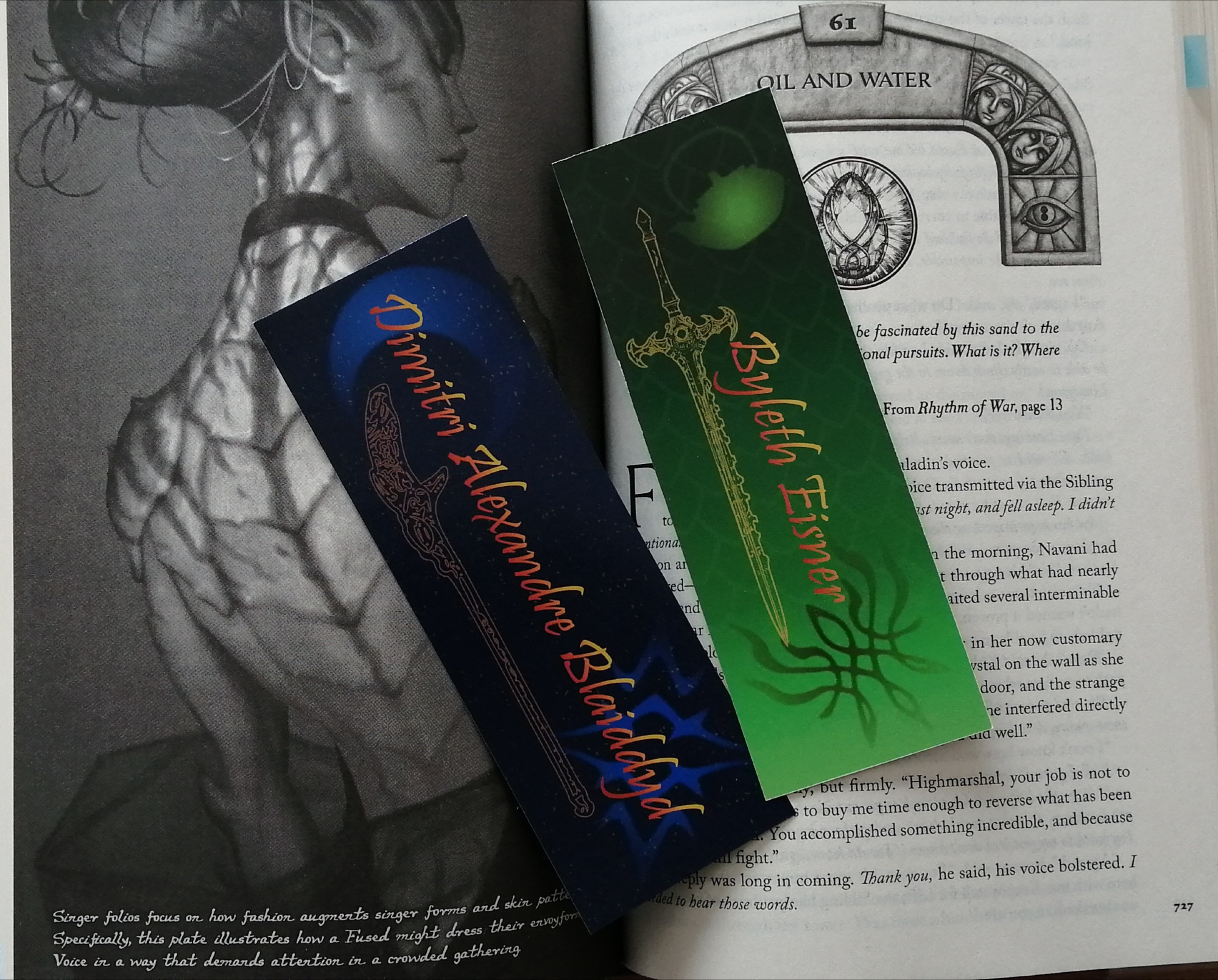 Dimileth bookmarks. One is blue with a lighter cresend moon and the crest of Blaiddyd and the lance Areadbhar. Text reads Dimitri Alexandre Blaiddyd. The other bookmark is green with the Crest of Flames, a tea kettle and the Sword of the creator. Text reads Byleth Eisner