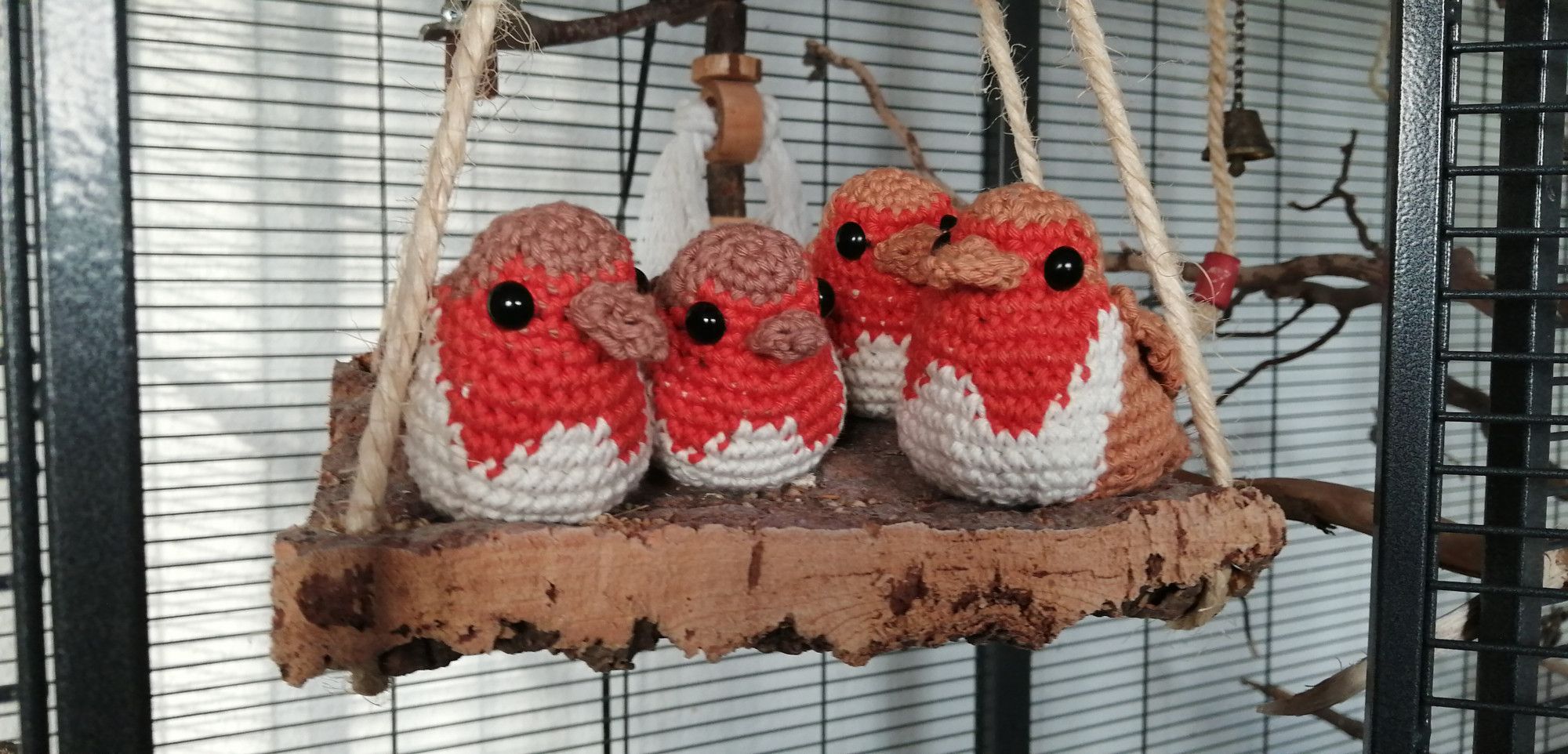 crocheted robins on a bird swing in a cage