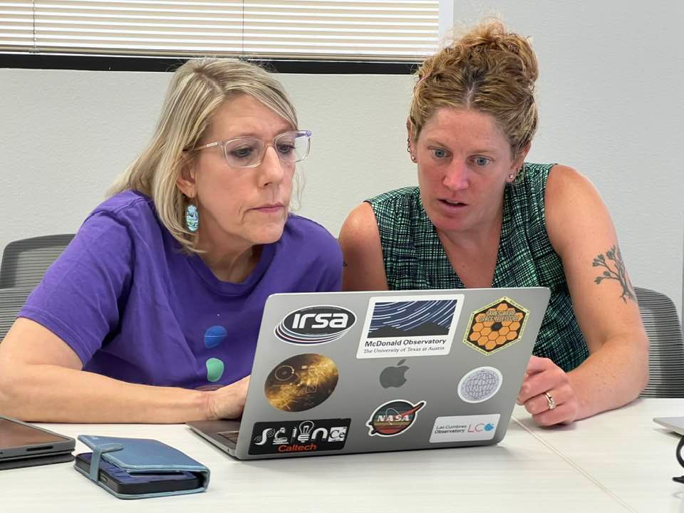 Two women educators working intently on astronomy data on a laptop