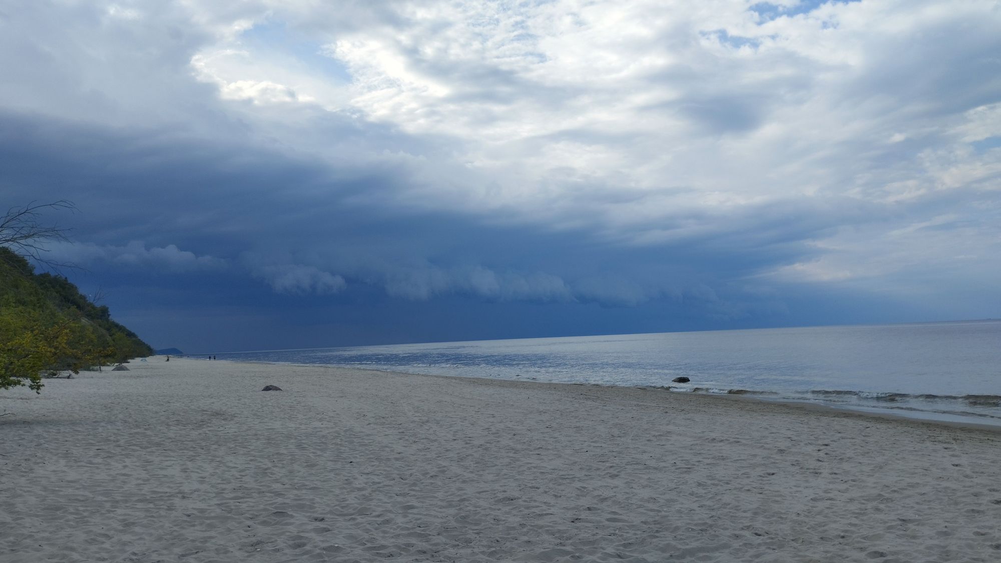 Ein Gewitter Naht an einem Sandstrand. Dunkle Wolken nähern sich dem Betrachter