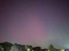 The Northern Lights shade the night sky pink and green.