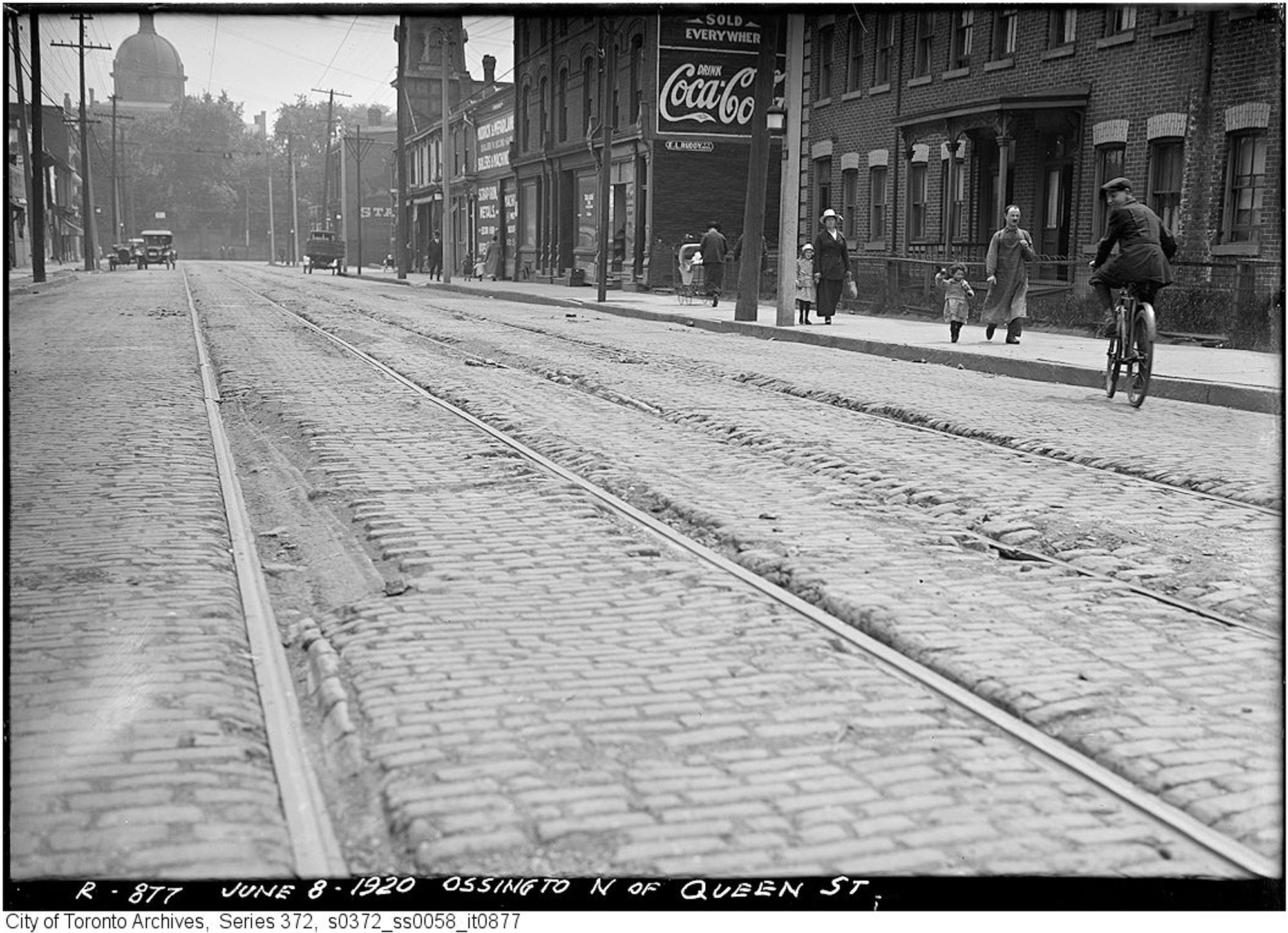 Black and white photo looking down a street with streetcar tracks.