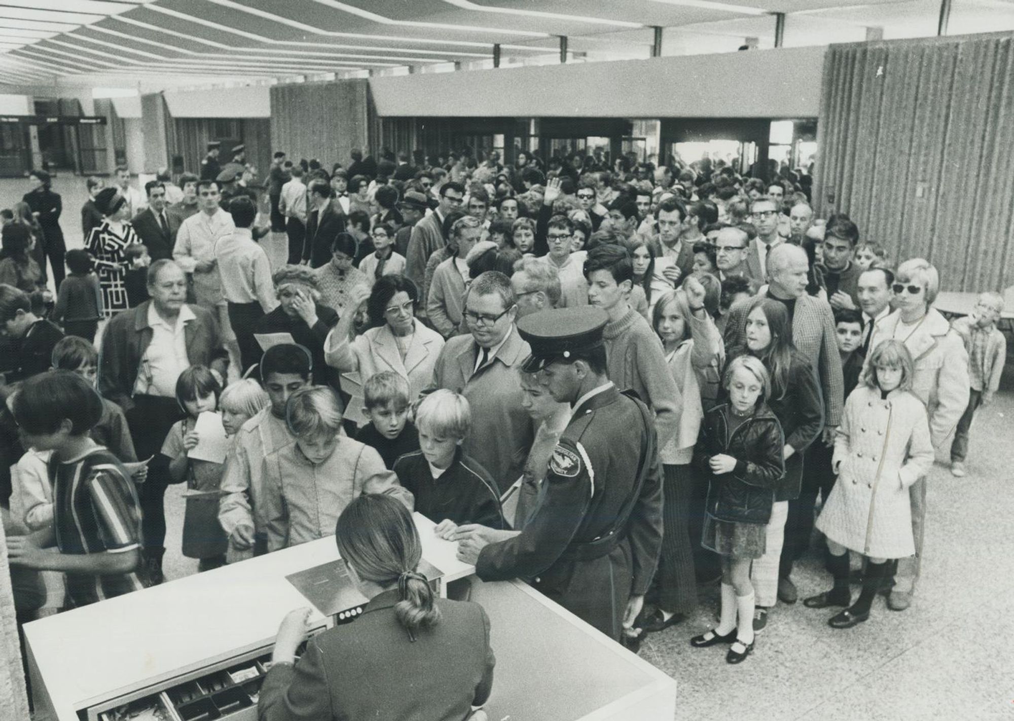 Black and white photo of a crowd of people in a modern building.