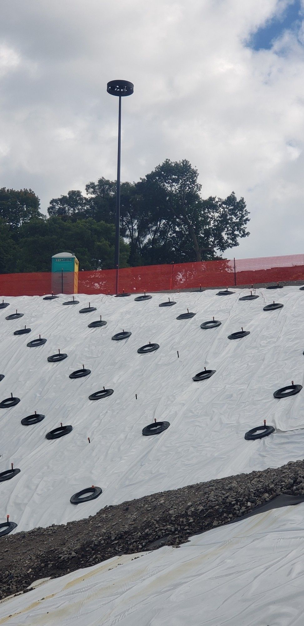 Looking up a hill covered in white plastic sheets, held down with plastic disks.