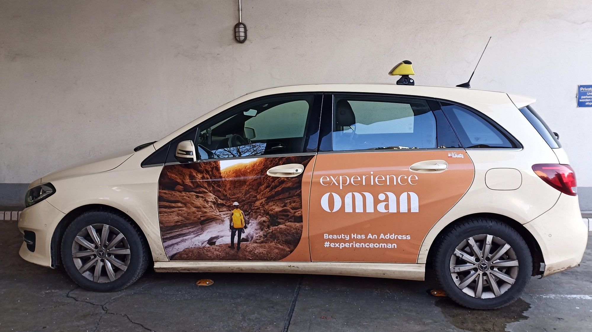 A taxi with a large advertisement covering both doors:

experience oman
Beauty Has An Address
#experienceoman